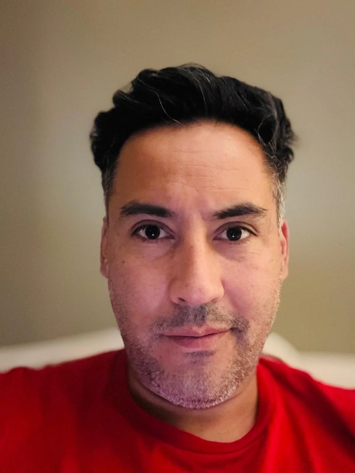 Silhouette of a young man standing outdoors at sunset with mountains in the background.