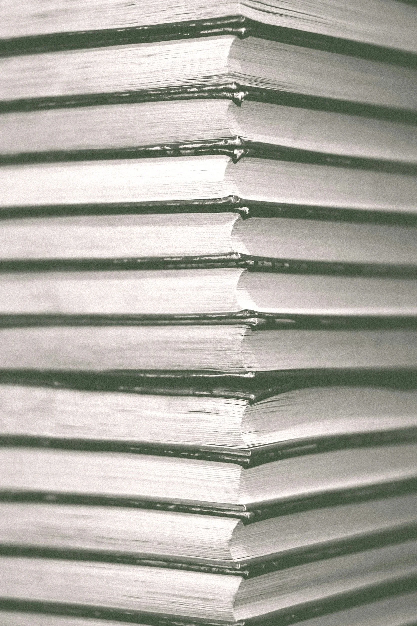 Stacked paperback books with visible pages and spines, arranged vertically.