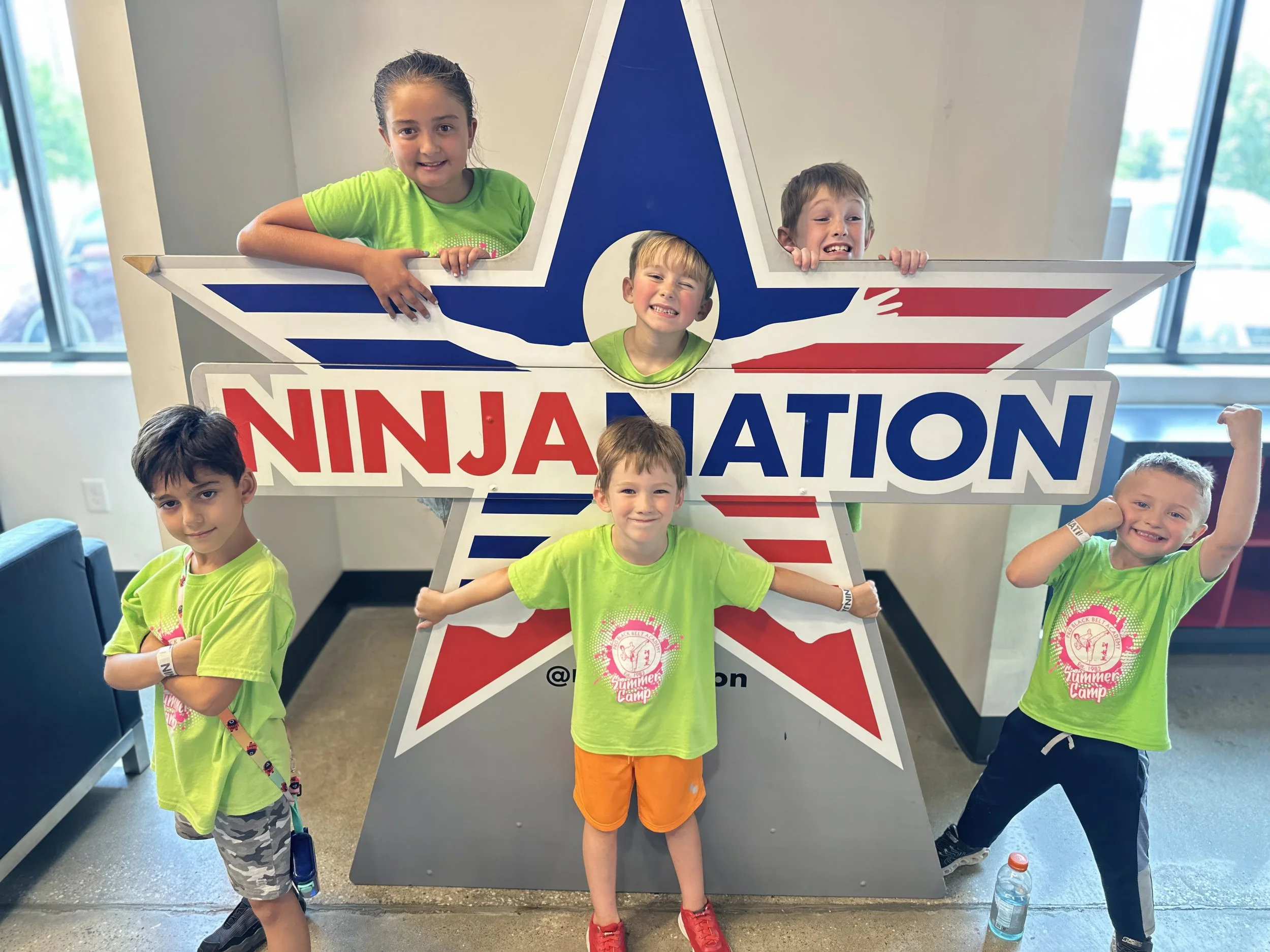 Group of children at an indoor event with a large 'NINJA NATION' star-shaped sign.
