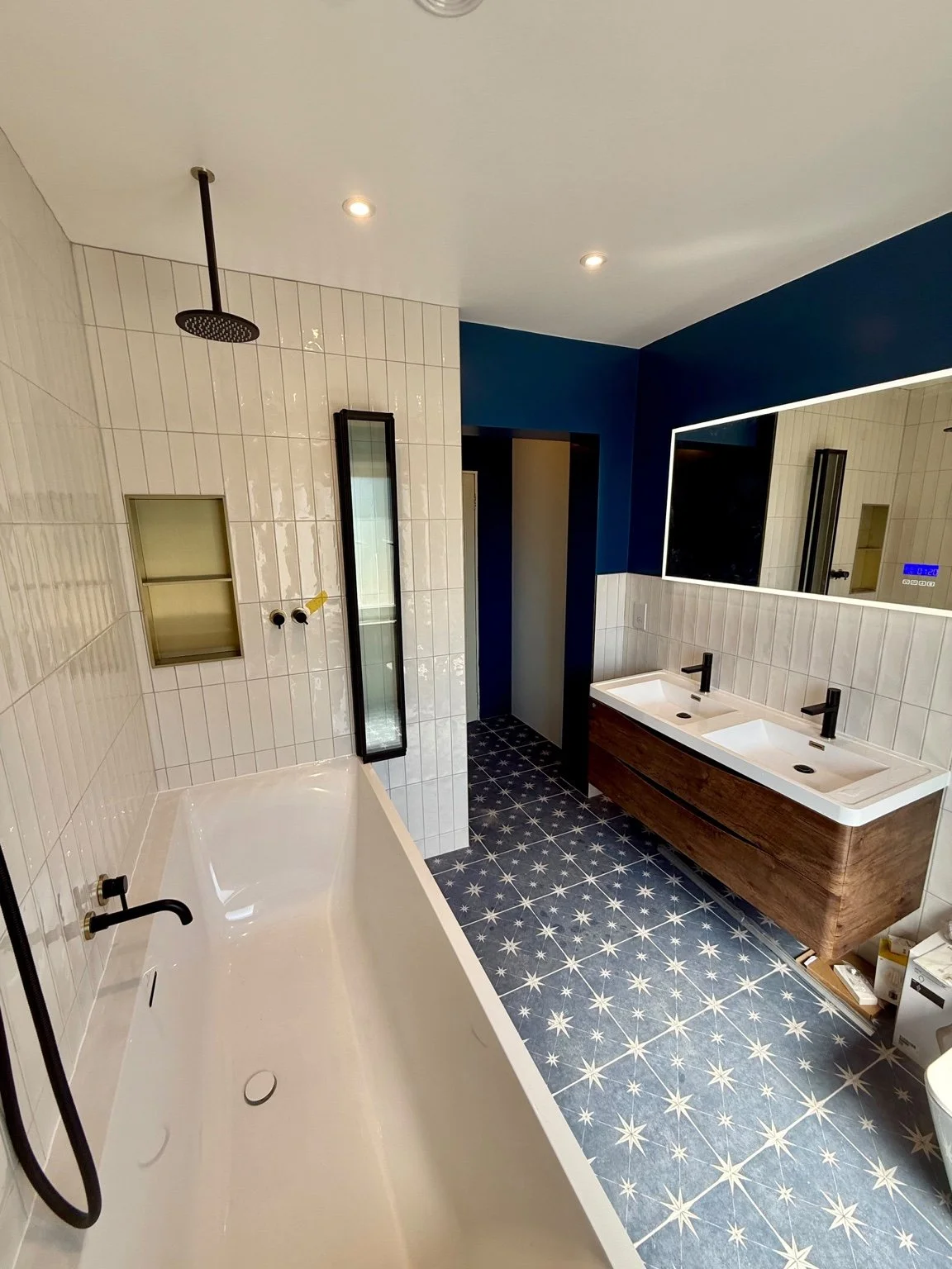 Bathroom with bath, ceiling mounted rain shower, illuminated mirror and downlights