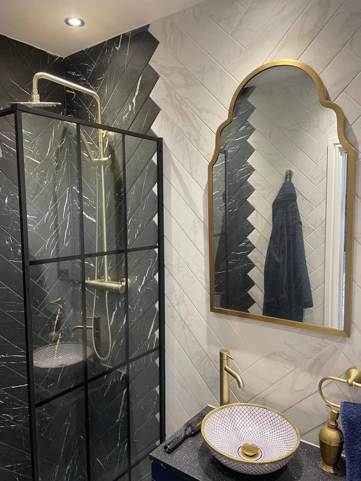 Bathroom basin with brass tap, arched mirror and recessed ceiling lights