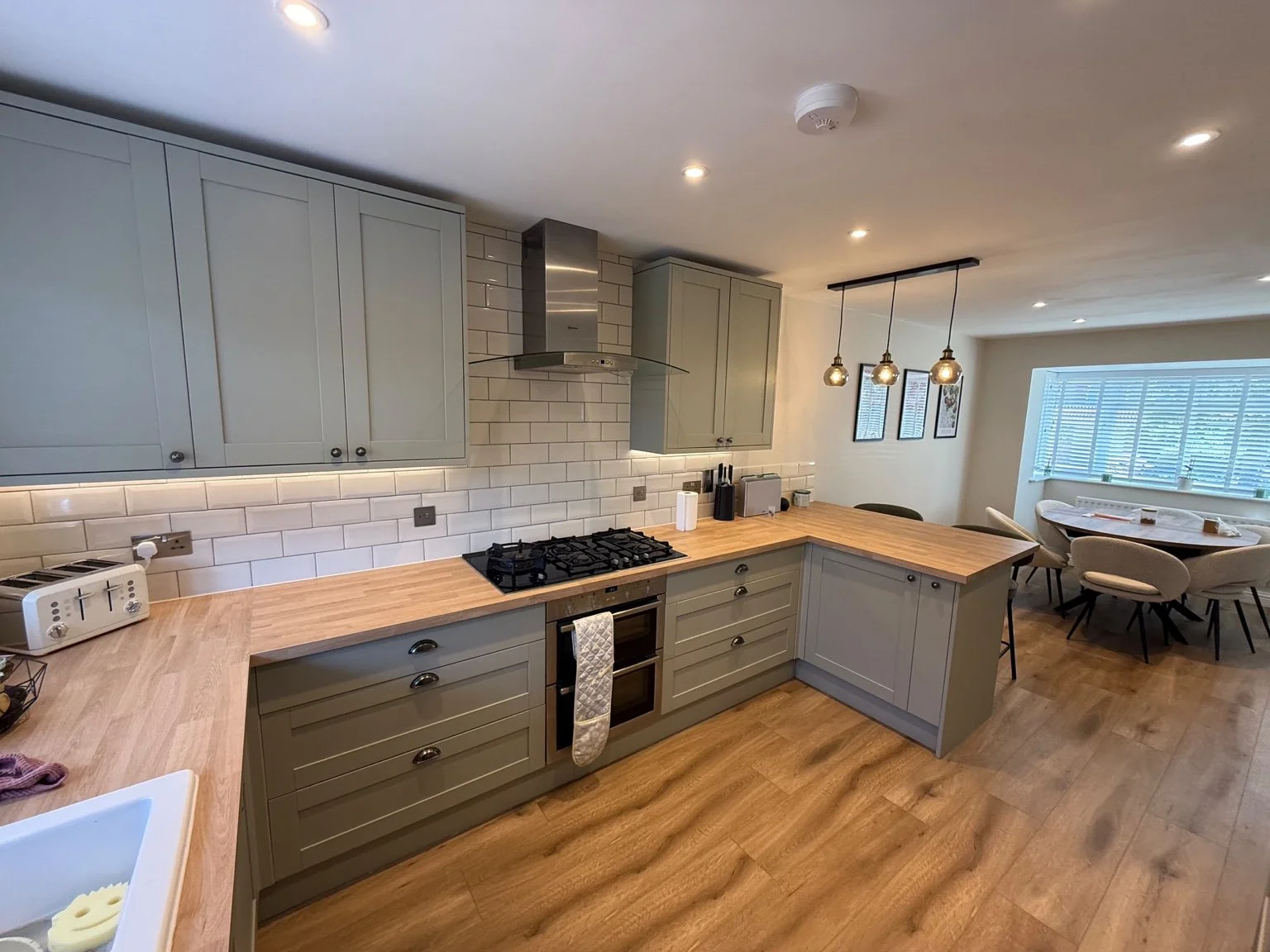 Grey kitchen with three pendant lights over the island and a cooker hood