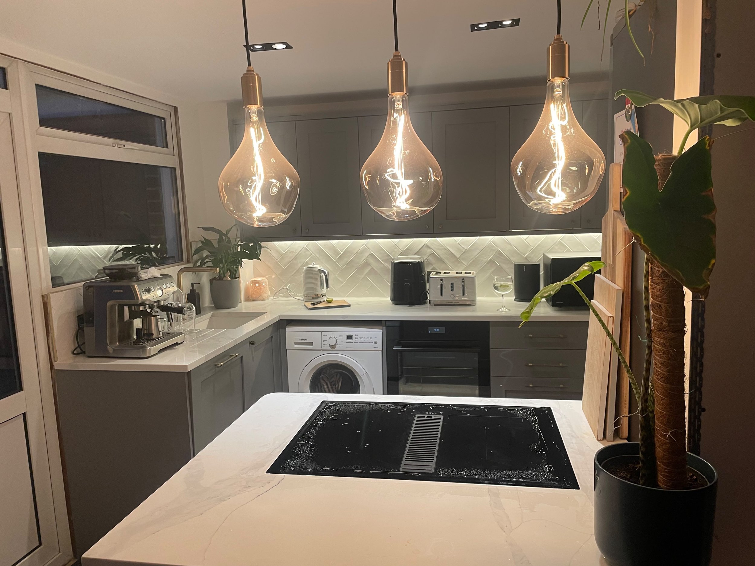 Kitchen with induction hob, filament pendant lights and under cabinet lighting