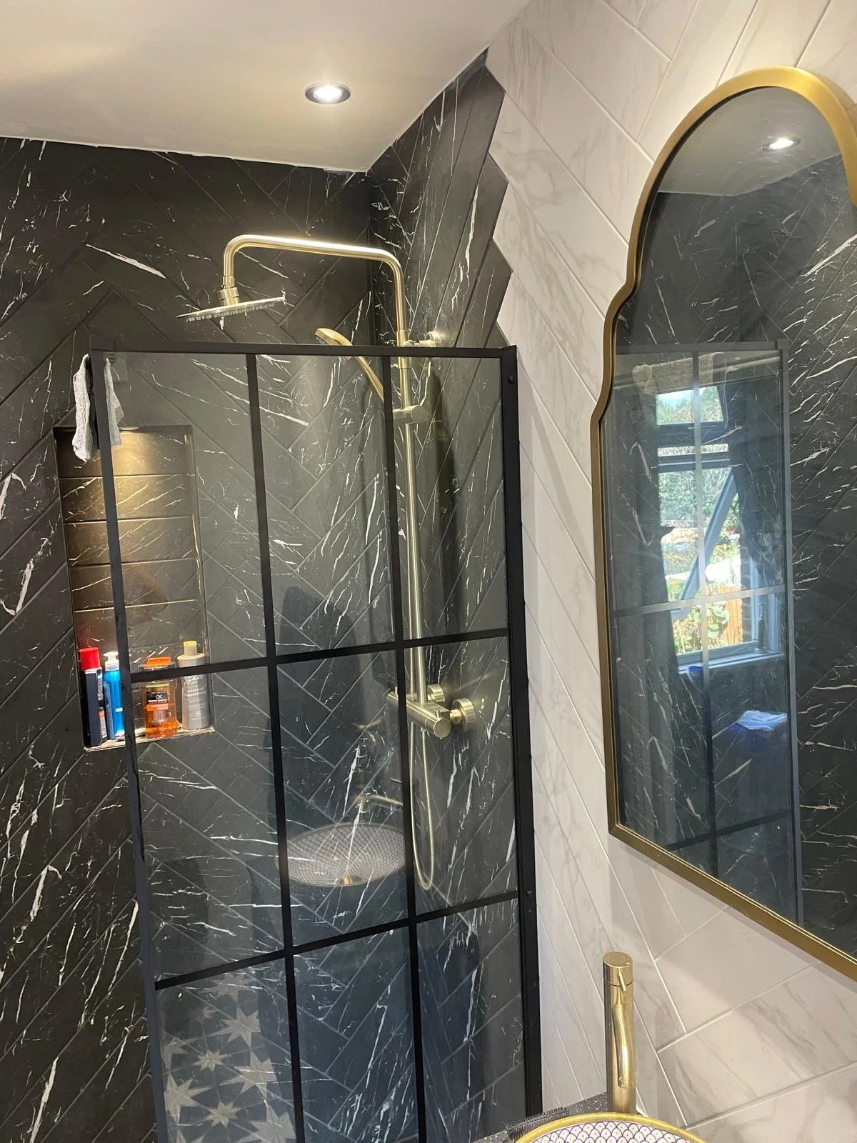 Shower enclosure with dark marble tiles, brass shower fittings and ceiling spotlights