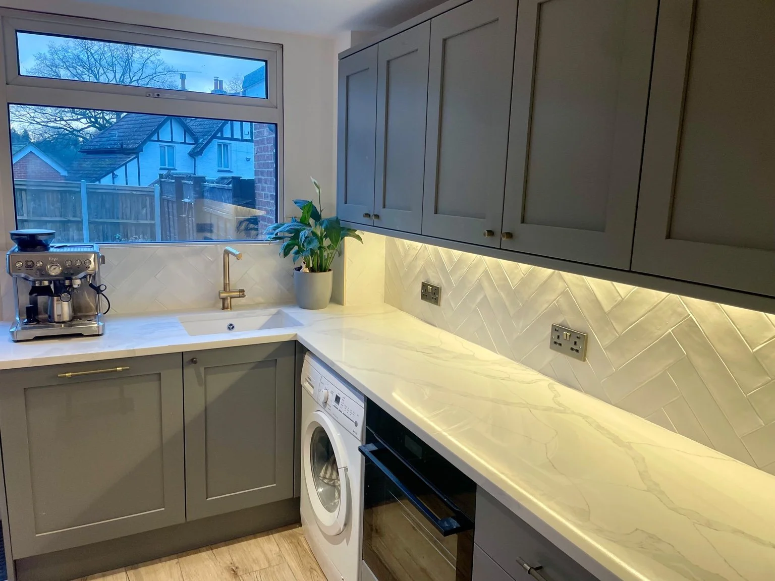 Kitchen worktop with sockets, a washing machine and a herringbone tiled splashback