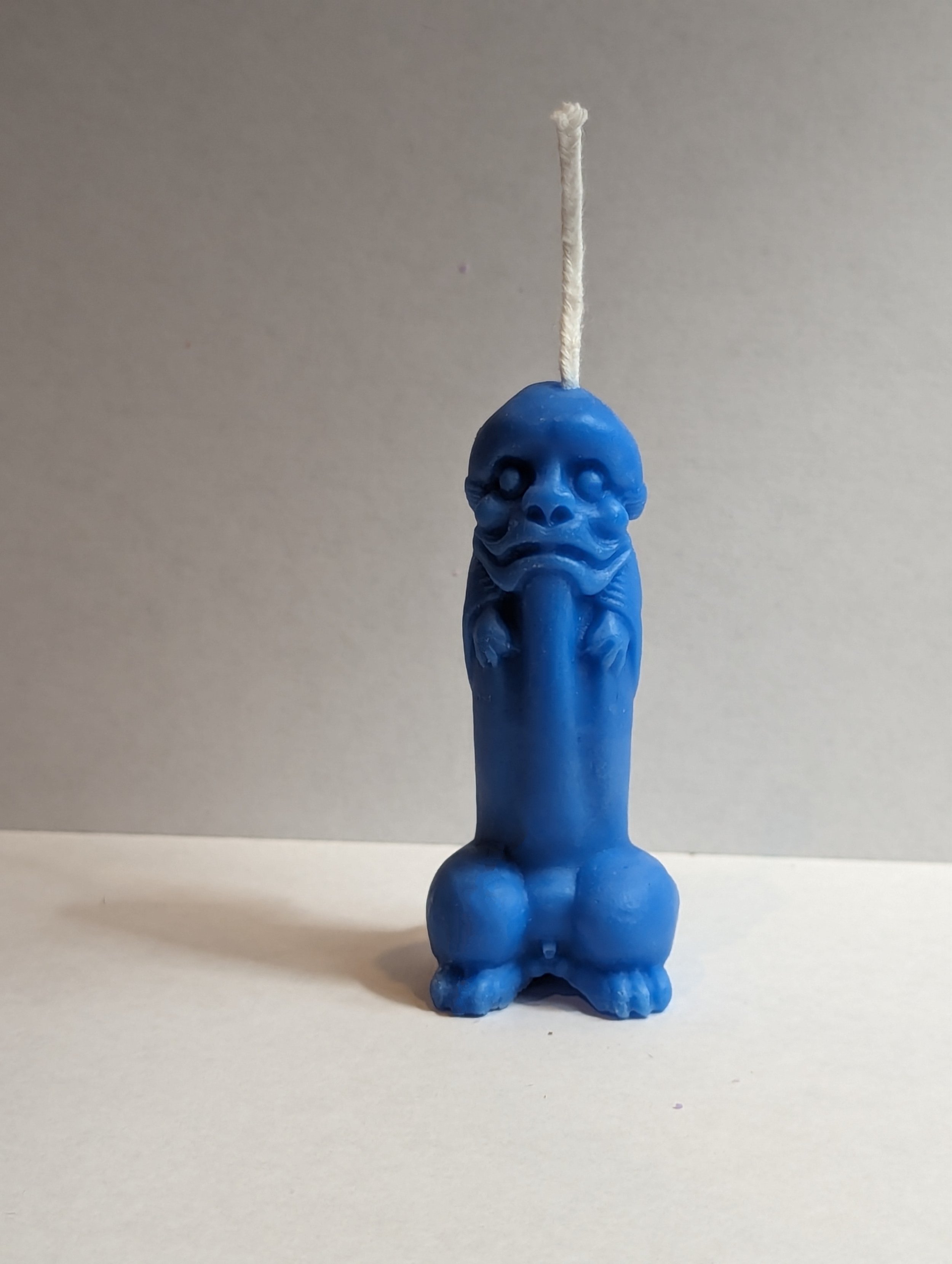 Blue candle shaped like a penis with a face.