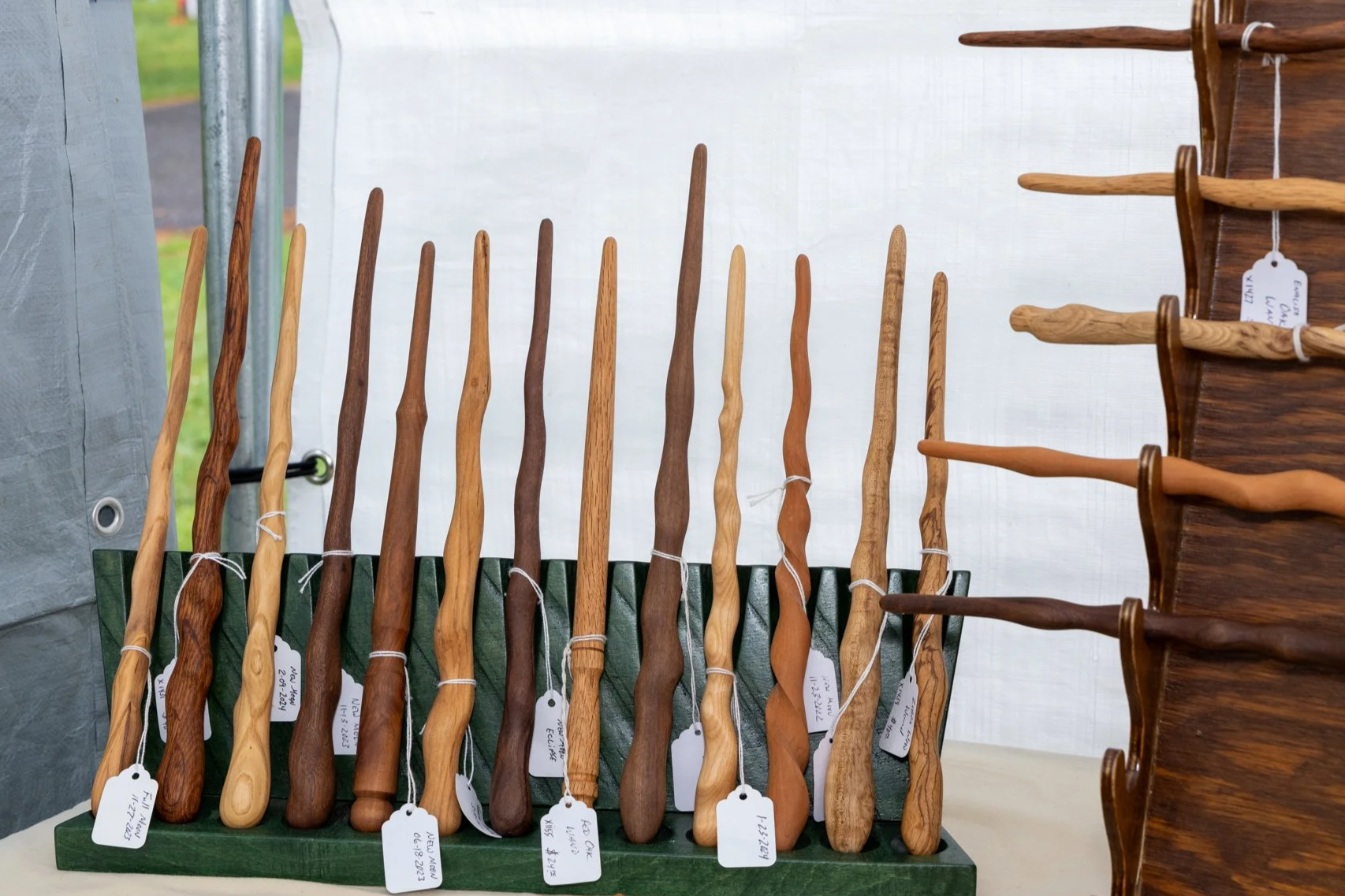 Collection of wooden kitchen utensils, including spoons and spatulas, arranged on display shelves at a craft fair.