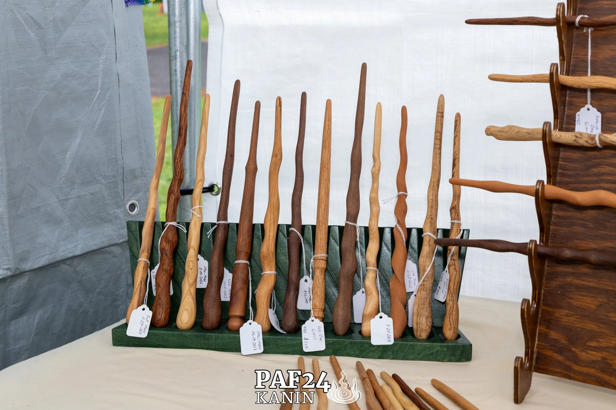 Collection of wooden wands displayed upright on green stand at a vendor market.