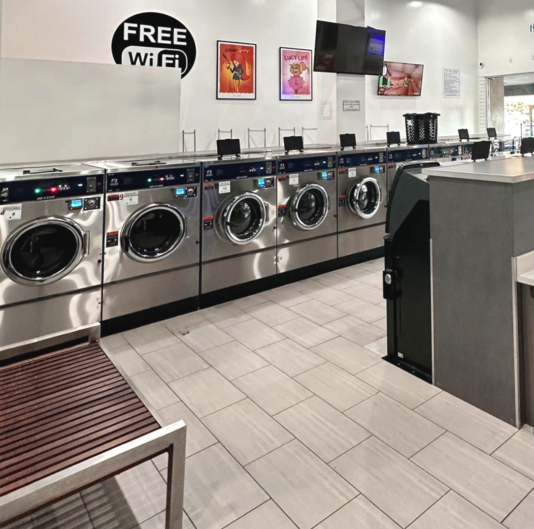 A clean laundromat in Davis, California with machines lined up against a wall, with a sign that says 'FREE WiFi' above them. Davis Laundry near me