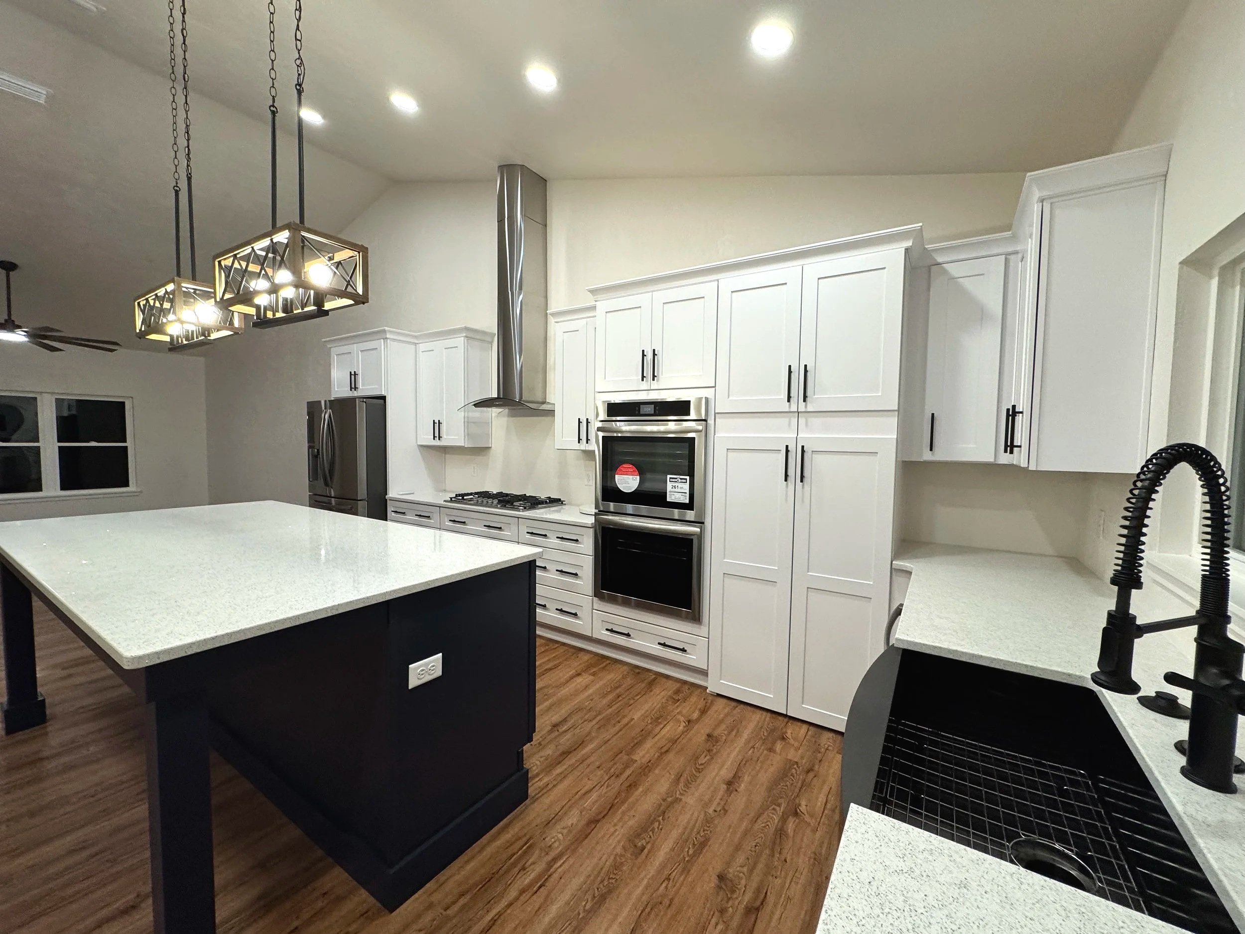 Newly built modern kitchen featuring white shaker cabinets, a large center island, stainless steel appliances, recessed lighting, and an open-concept layout with premium craftsmanship and finishes.