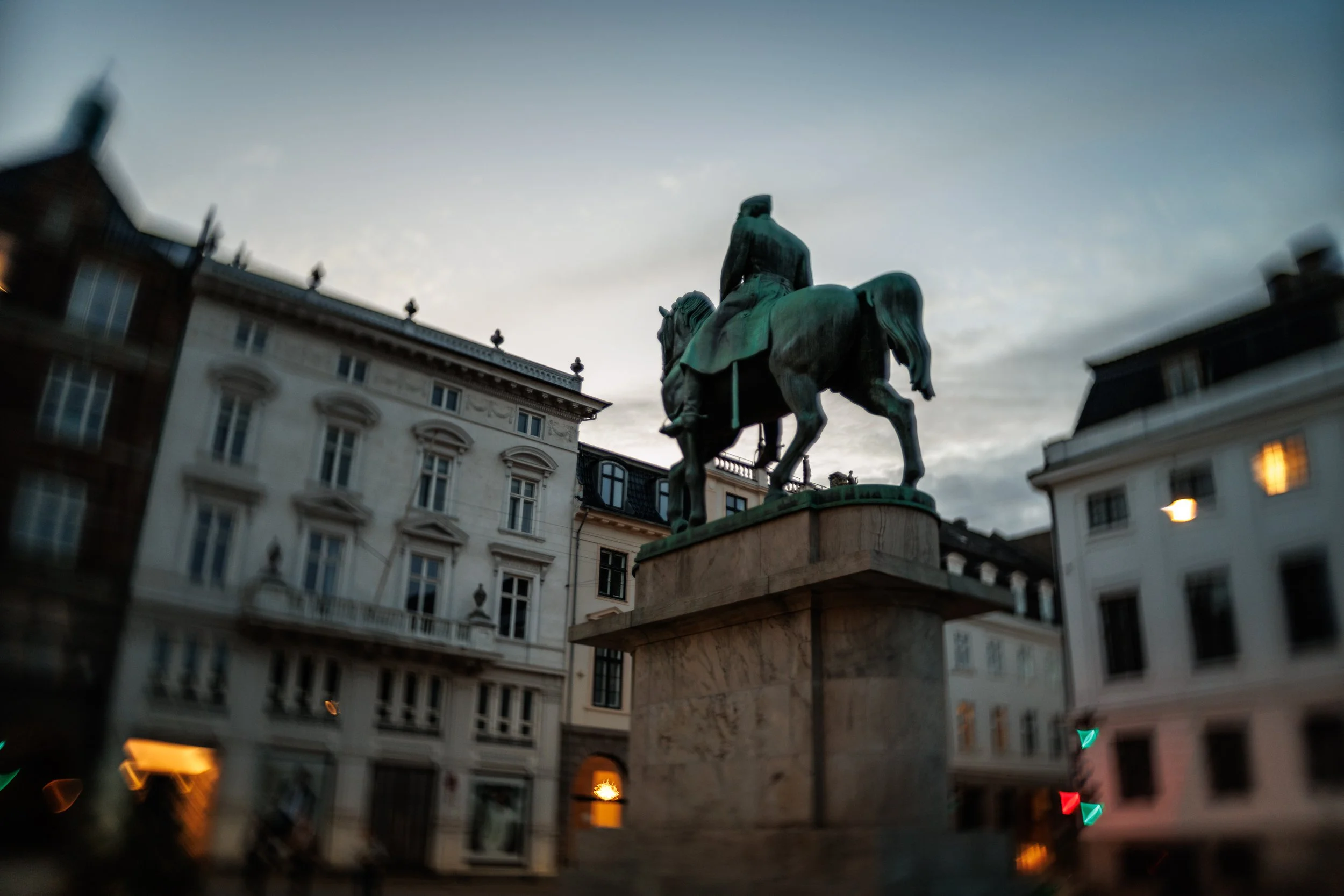 Bronze equestrian statue of a man on a horse located in a historic European city square with ornate buildings around.
