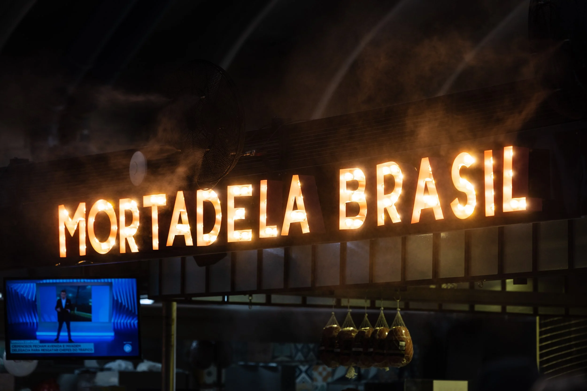 A neon sign reading 'MORTADELA BRASIL' in orange lights.