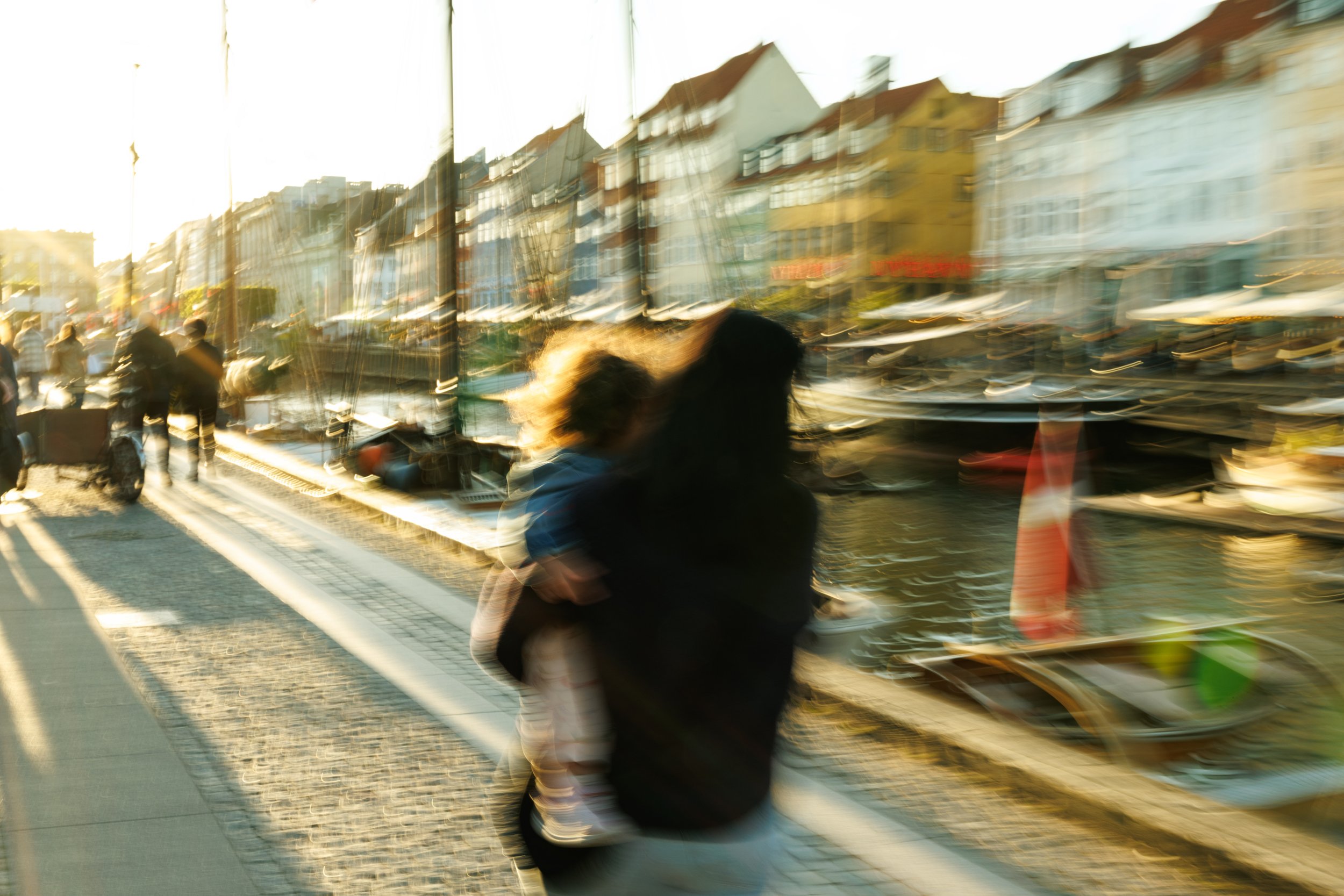 Blurred reflection of buildings and people on a window during sunset.