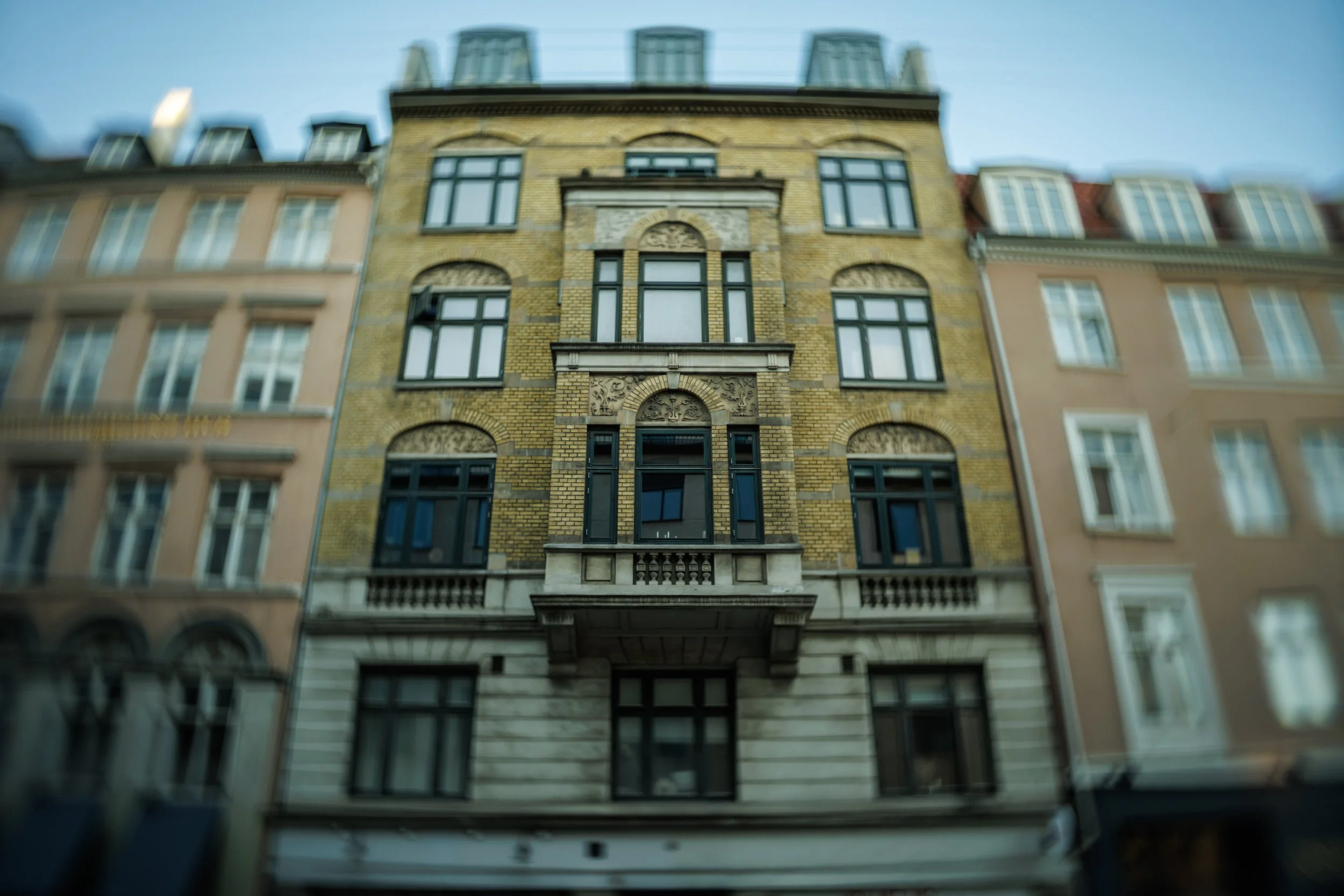 Multiple multi-story buildings with large windows and detailed architecture, viewed from a low angle with a clear sky.