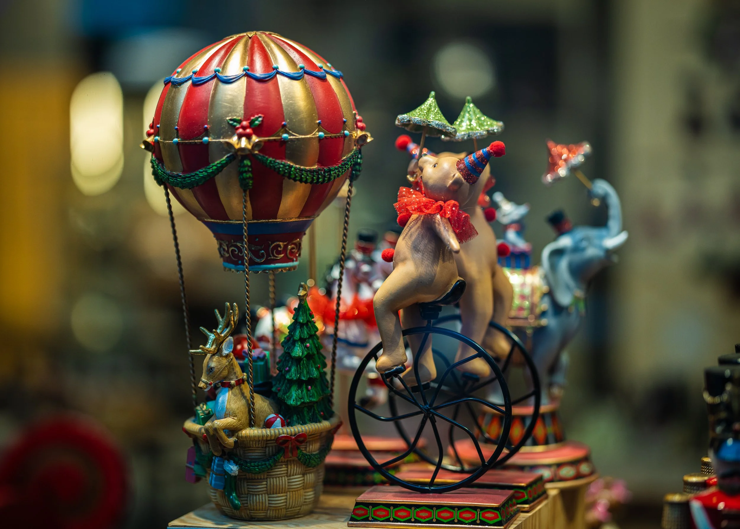 Decorative holiday figurines including a balloon, animals, and circus-themed items with vibrant Christmas colors.