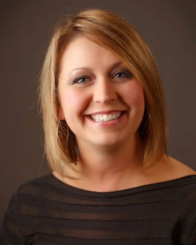 A smiling Portrait of Tina Longawa of Rosemont Project Management with shoulder-length red hair, wearing a black top.
