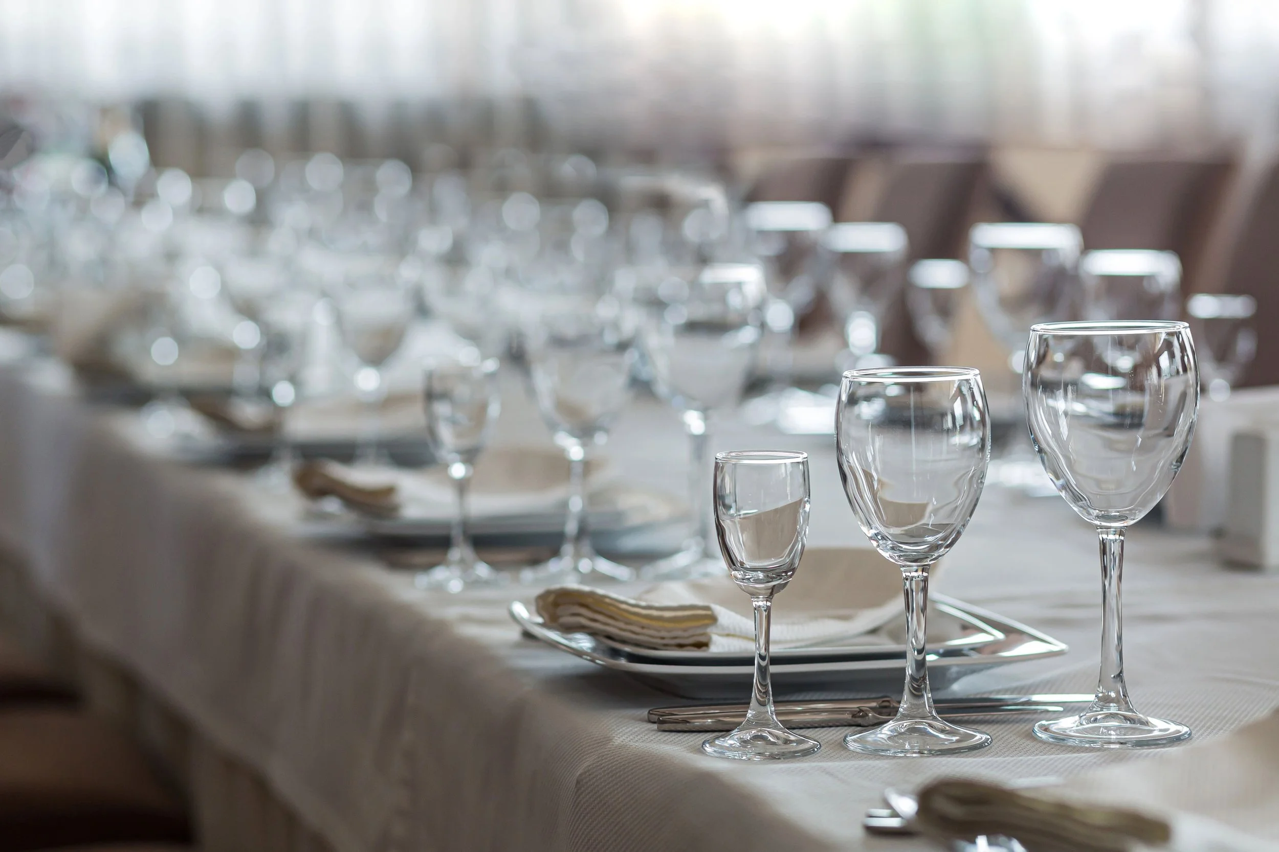 Empty wine glasses and tableware set on a banquet table, ready for a formal dining event at a hotel.