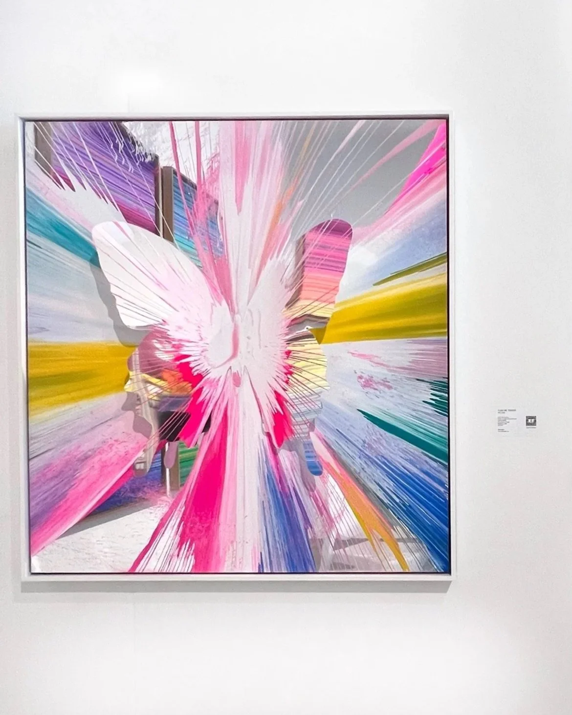 Colorful abstract artwork featuring a central hand gesture with starburst effects in pink, yellow, green, blue, and purple on a white background.