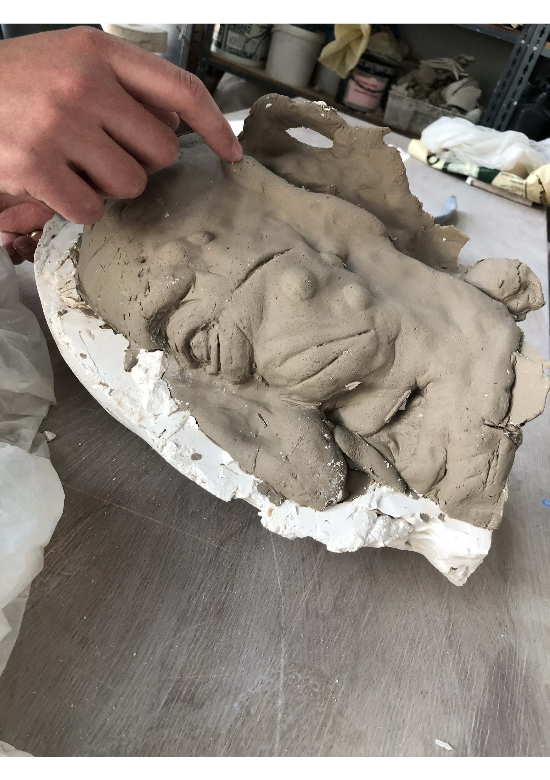 A person creating a clay sculpture of a human face.