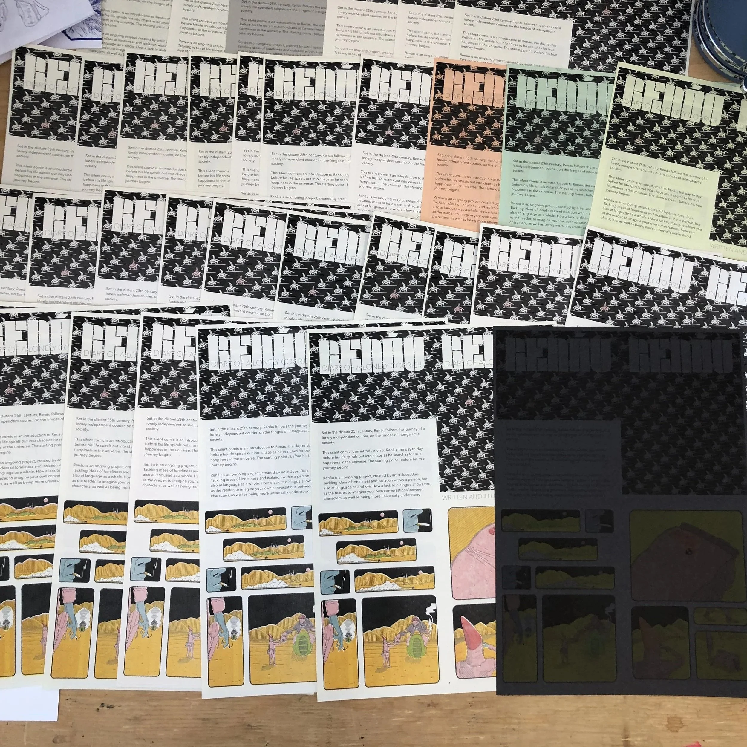 A collection of colorful comics laid out on a wooden surface, with some pages and papers in the background.