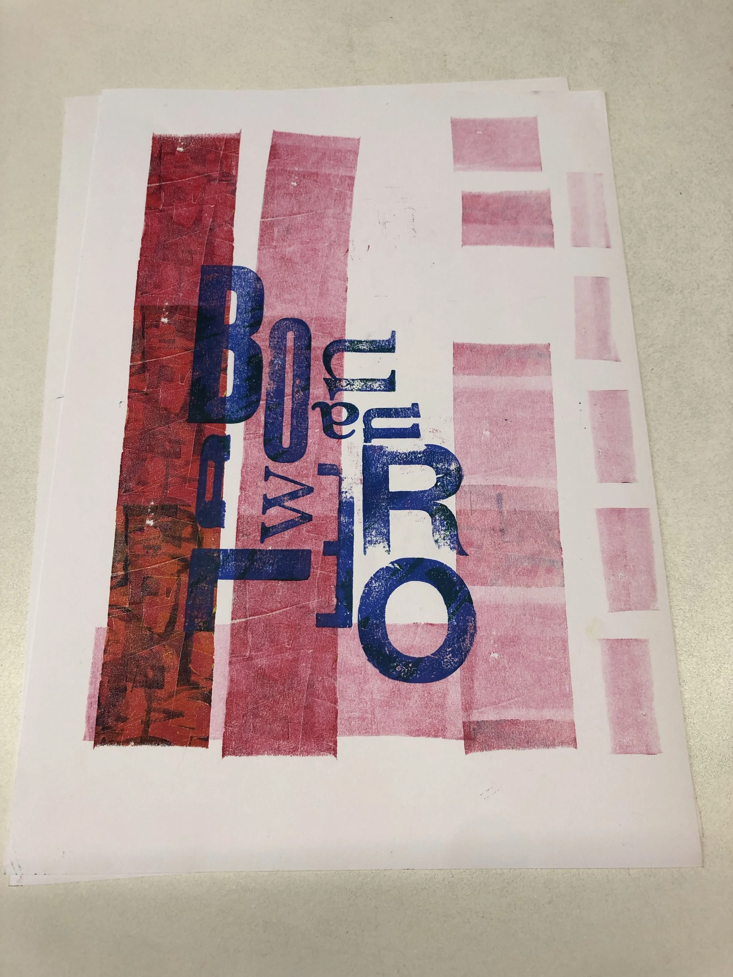 Close-up of a printed page with red, pink, and blue text and graphics on white paper placed on a gray surface.