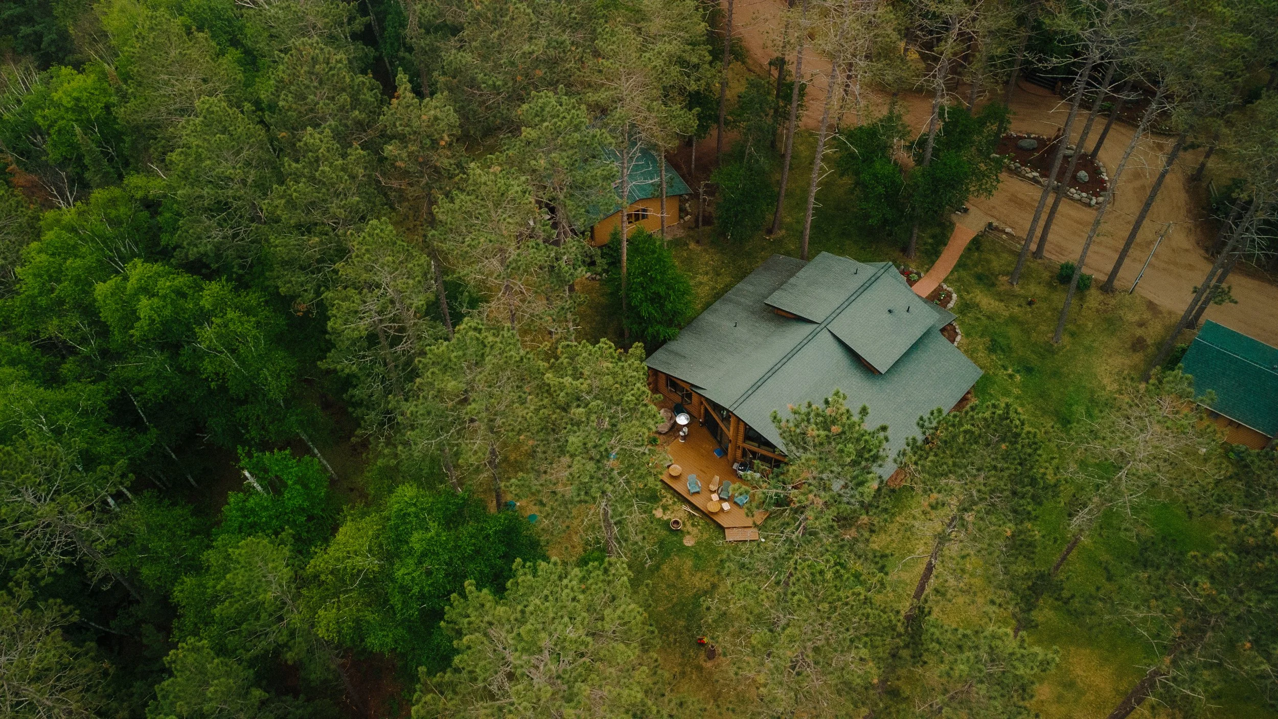 Aerial view of a house surrounded by a dense forest of tall green trees.