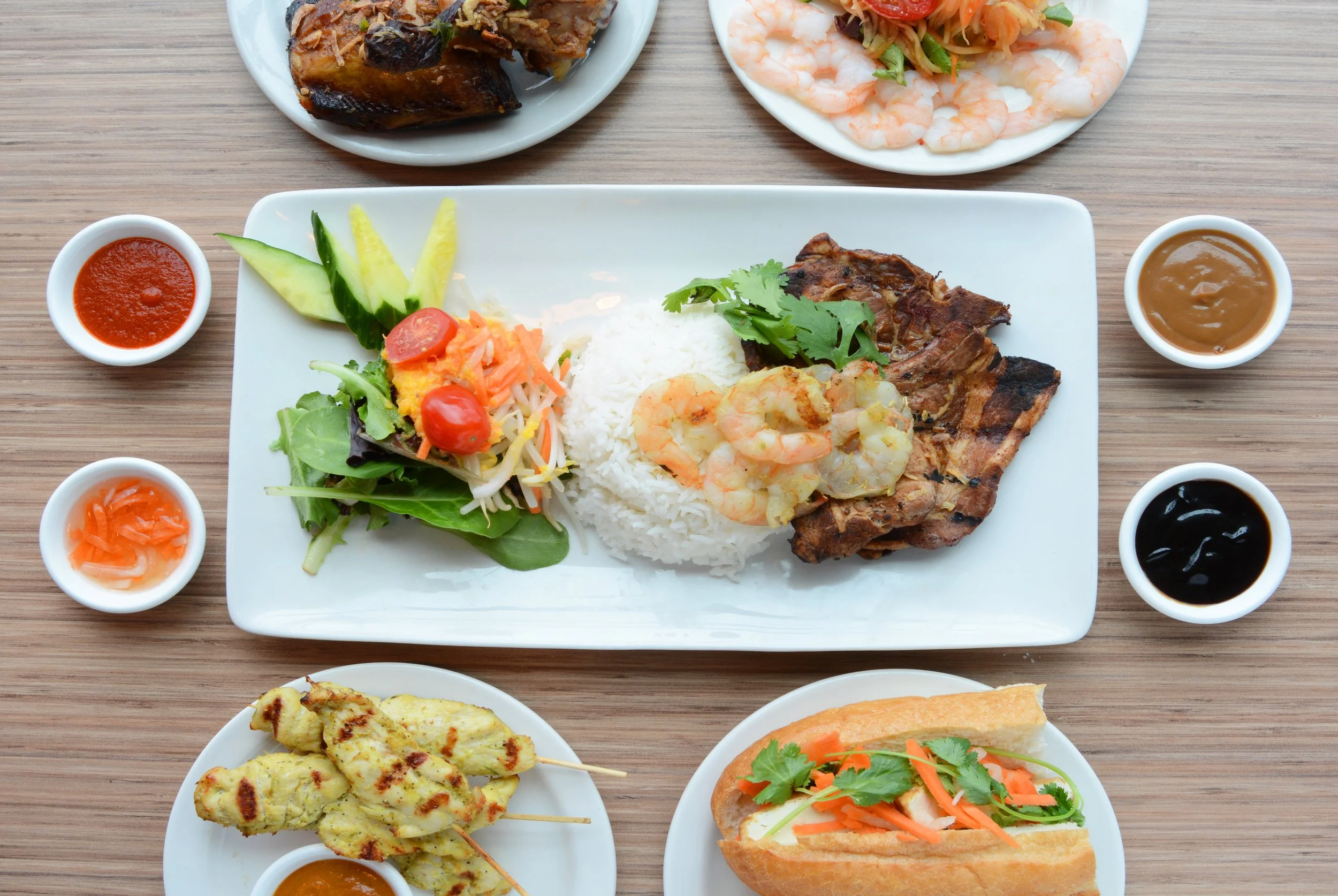 Plate of Vietnamese Surf & Turf with rice and salad, shown with dipping sauces and various other menu items