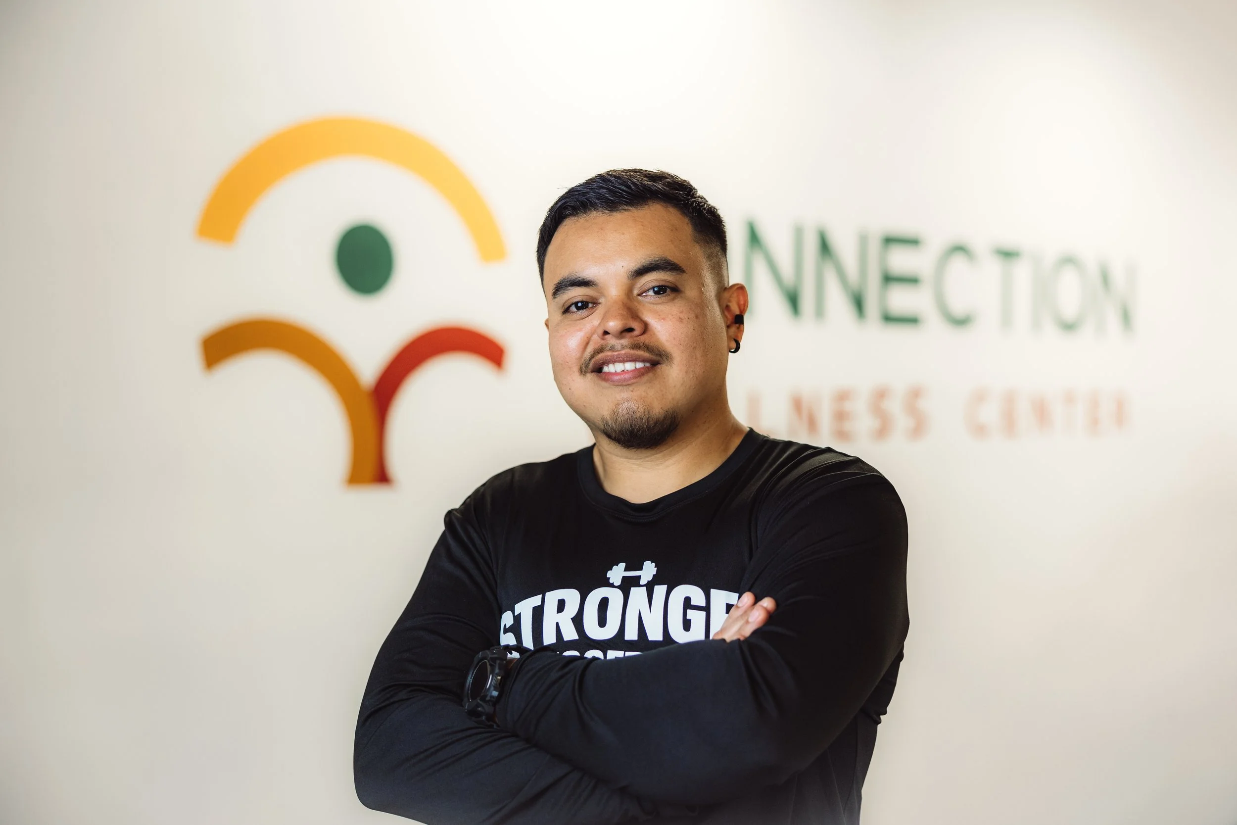 A smiling man with crossed arms in front of a wall with a logo and text that reads 'Connection Business Center'.