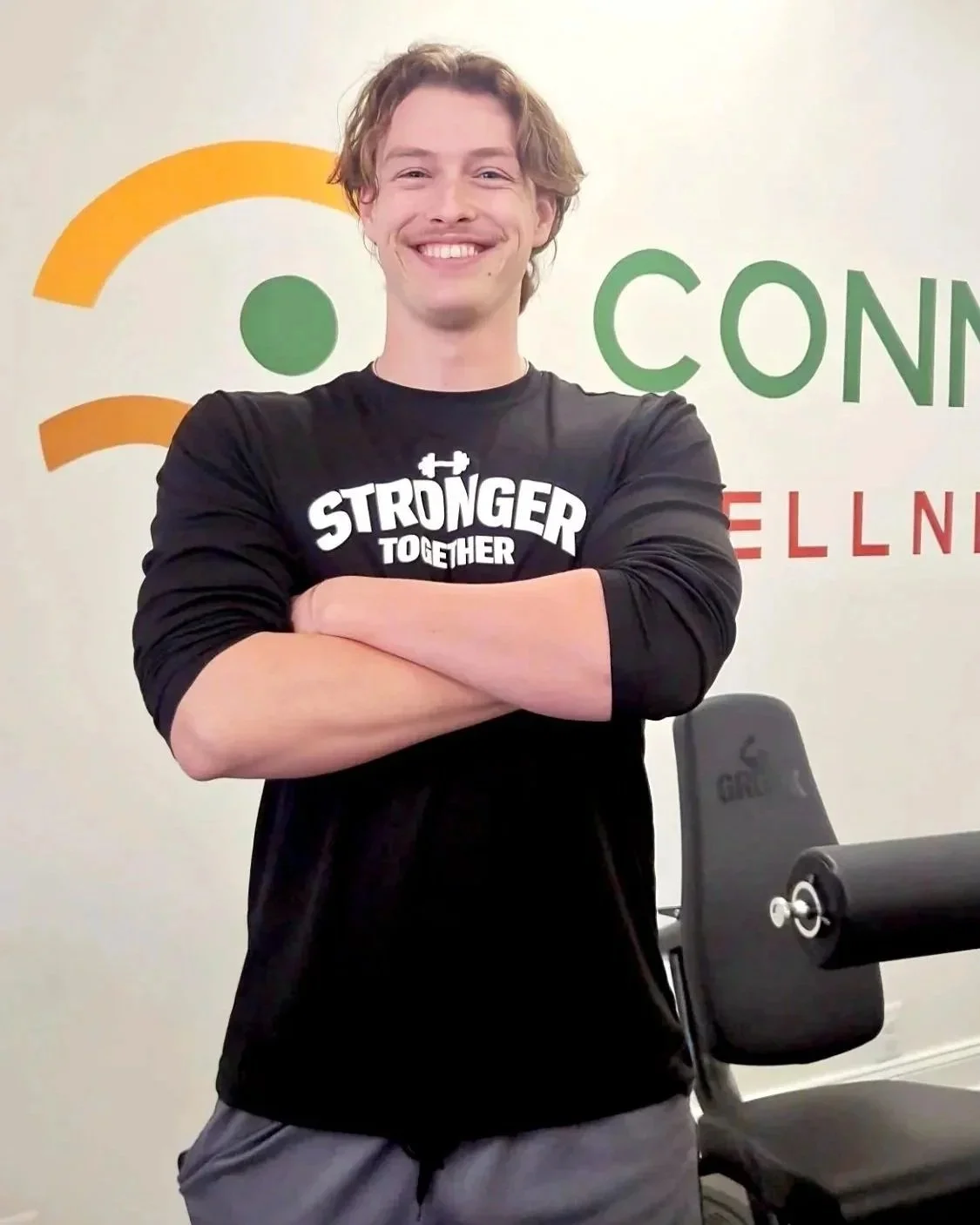 A smiling man with crossed arms in front of a wall with a logo and text that reads 'Connection Business Center'.