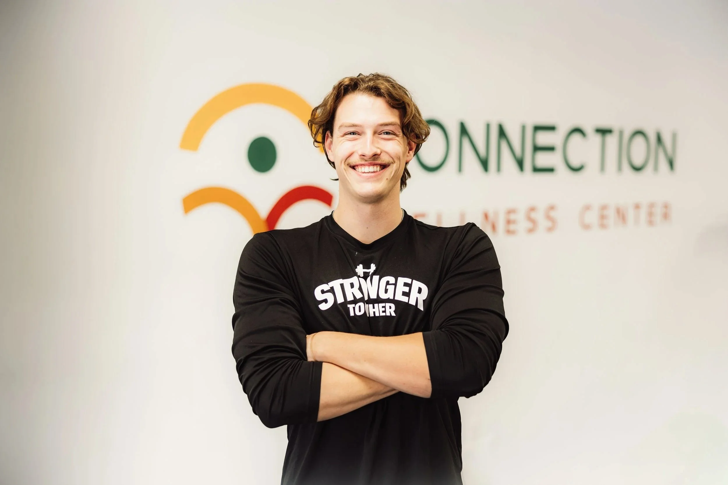 A smiling man with crossed arms in front of a wall with a logo and text that reads 'Connection Business Center'.