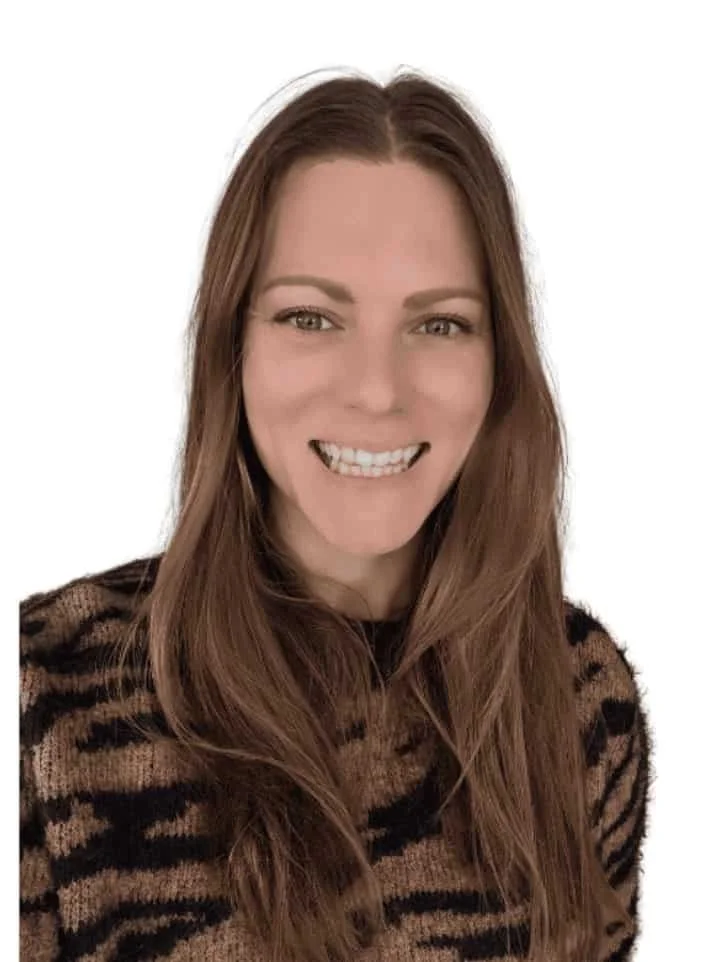 A young woman with long brown hair smiling, wearing a black and brown animal print sweater, against a plain white background.