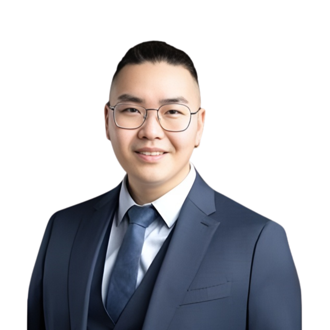 Portrait of a young man in a navy suit, white shirt, and tie, wearing glasses, smiling against a white background.