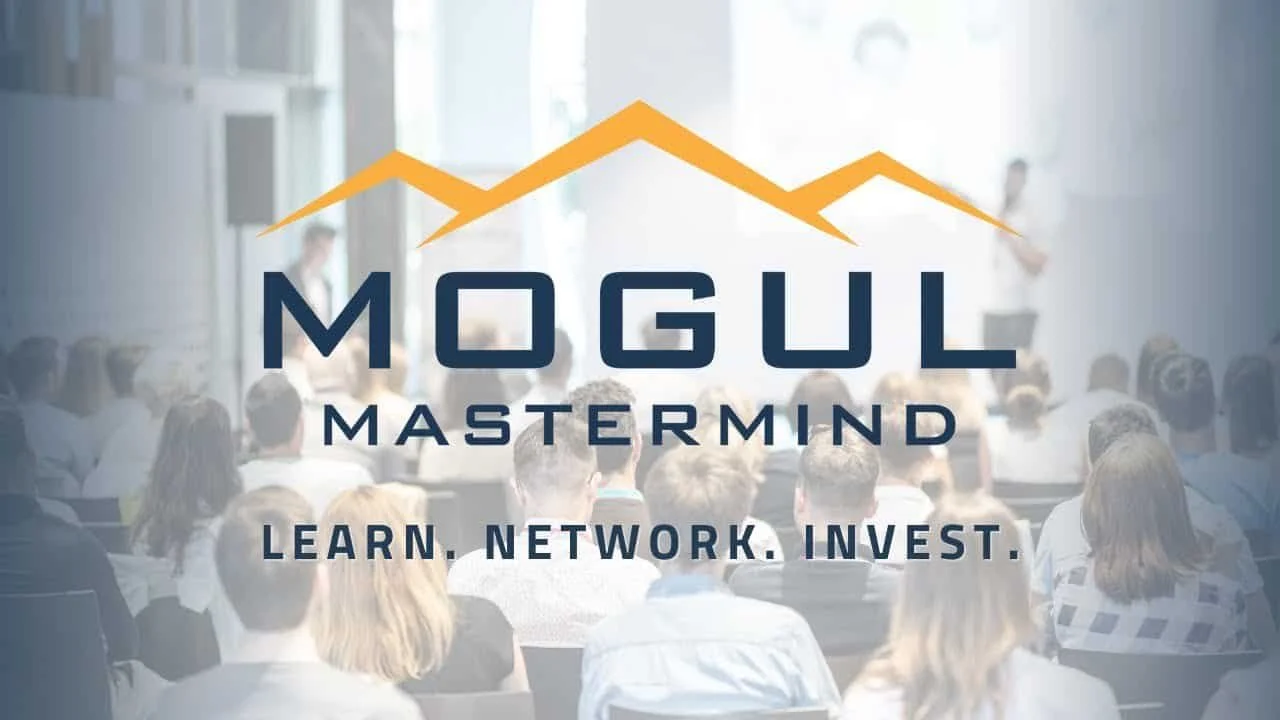 A conference room full of people attending a seminar, with a presentation screen displaying the logo 'Mogul Mastermind' and the tagline 'Learn, Network, Invest' over a blurred background.