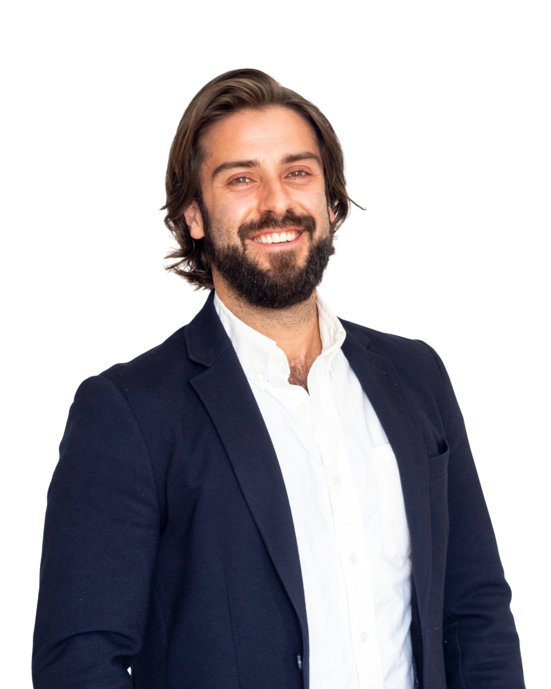 A smiling man with shoulder-length brown hair and a beard, wearing a dark blazer and white shirt, standing against a white background.