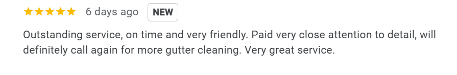 A modern house with wooden and stone exterior on a grassy hill, with snow-capped mountains in the background and a cloudy sky.