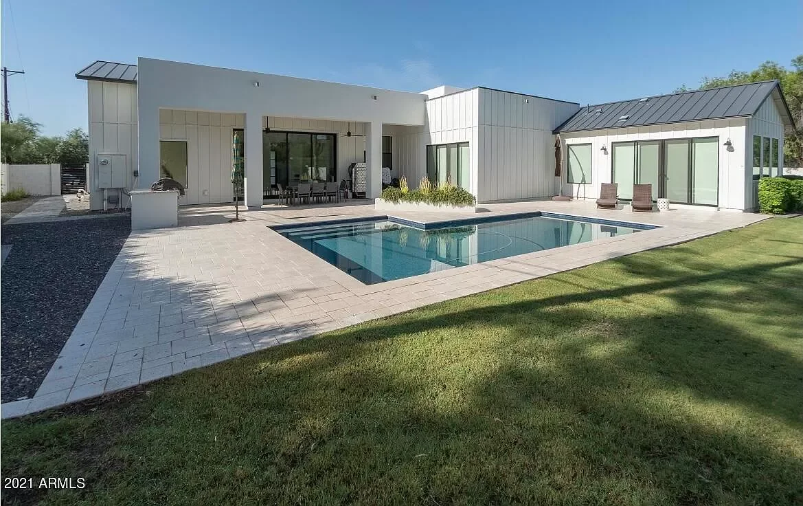Modern house with a backyard swimming pool, patio area, and outdoor seating.