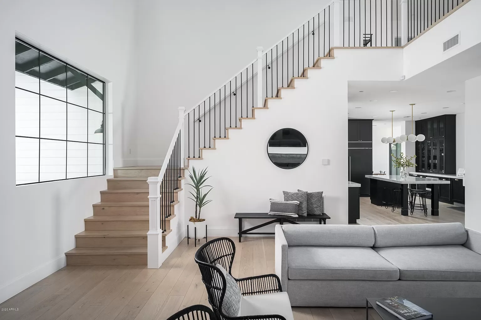 Modern Phoenix custom home interior with white oak floors, black-and-white staircase, open living room, and kitchen with dark cabinetry and brass lighting