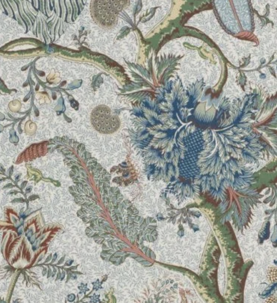 Close-up of a detailed floral and botanical pattern with large blue flowers, green leaves, and smaller blossoms in a tapestry or fabric design.