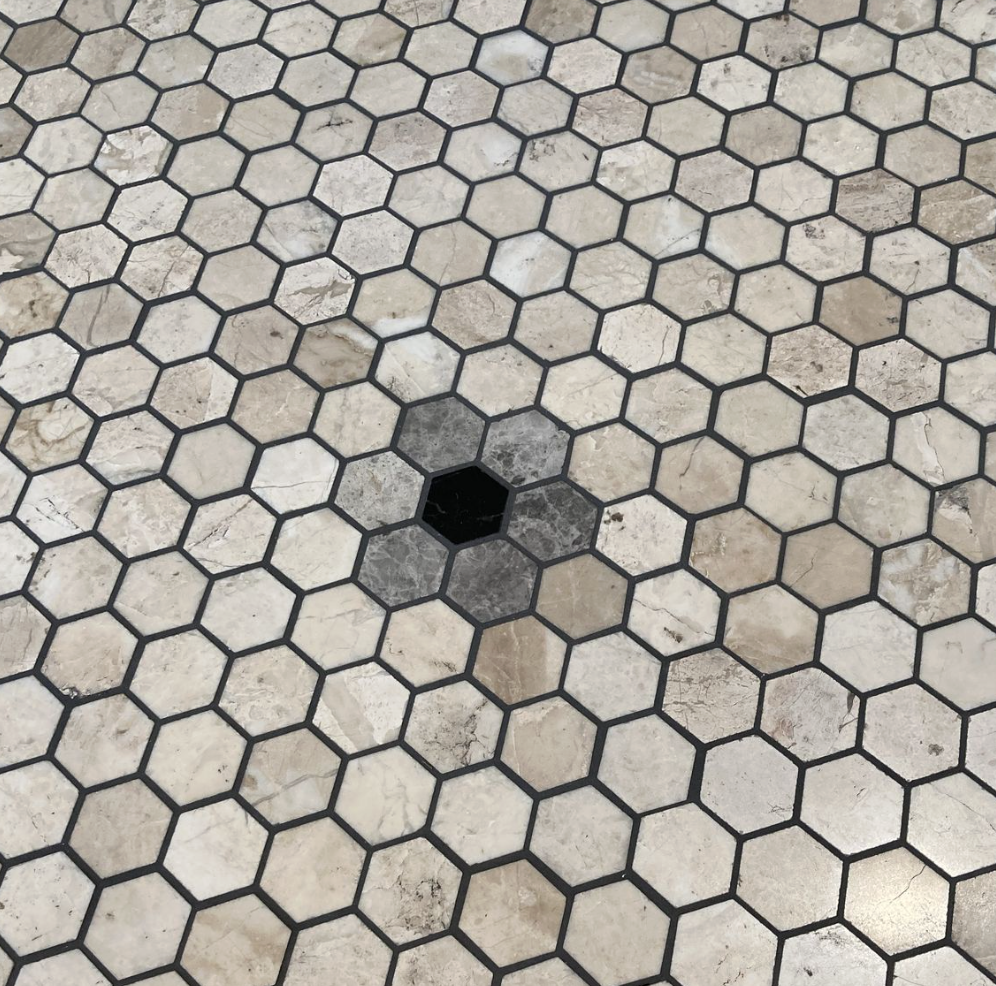 Hexagonal tiled floor with a single black tile in the center.