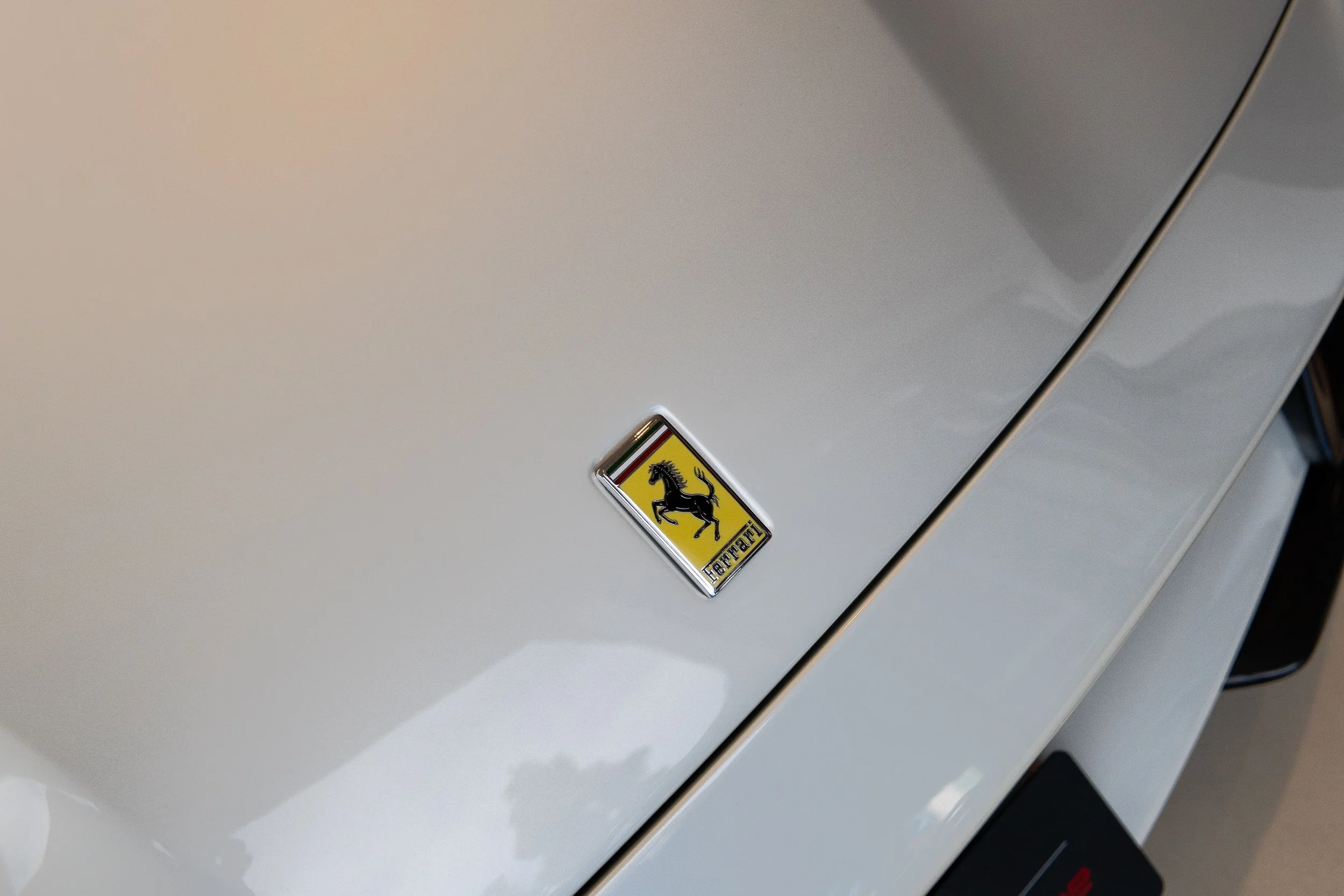 Close-up of a white sports car with a Ferrari emblem on the hood.