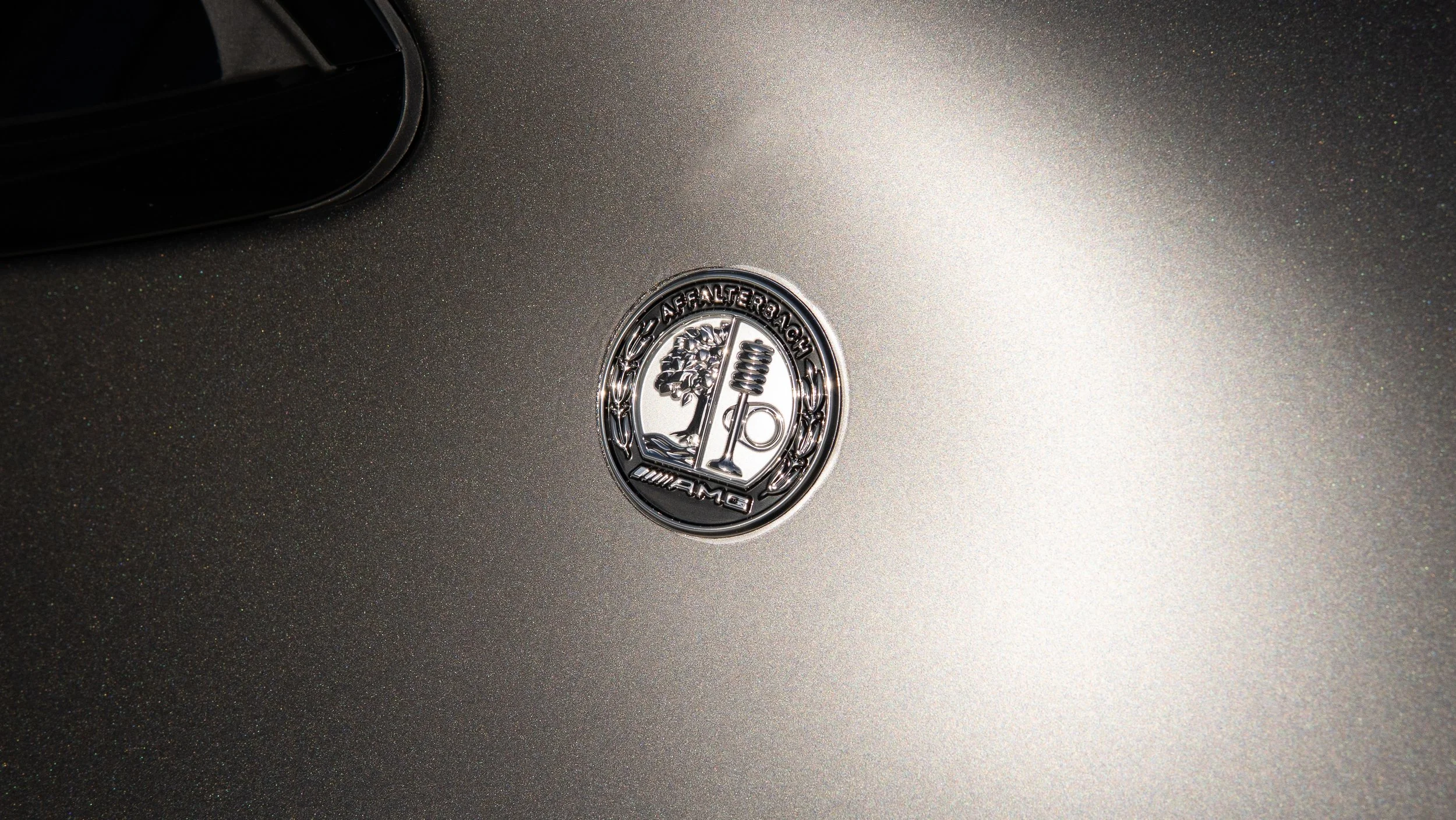 Close-up of a Mercedes-Benz AMG emblem on a metallic gray car surface.