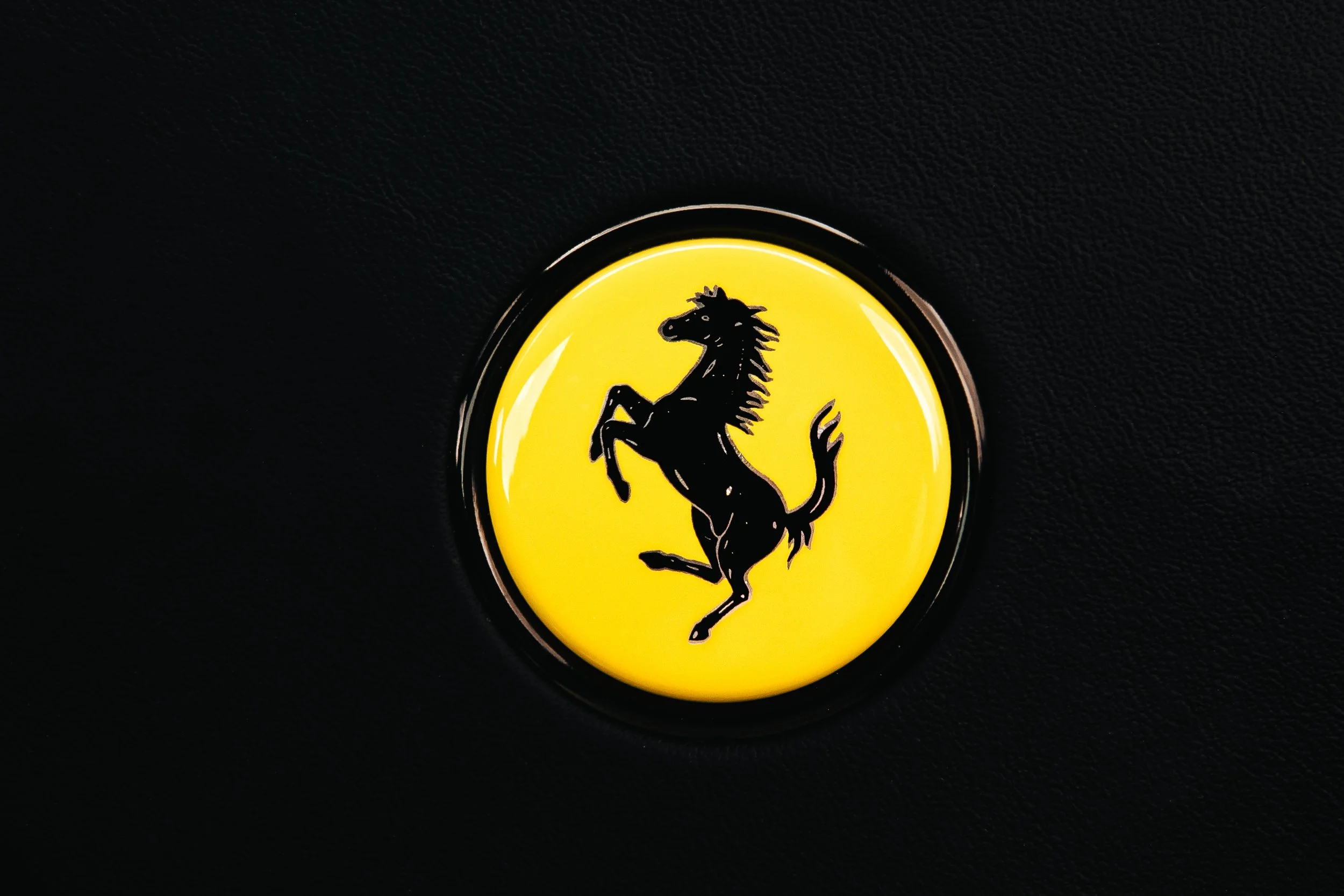 Ferrari logo featuring a black prancing horse on a yellow background.
