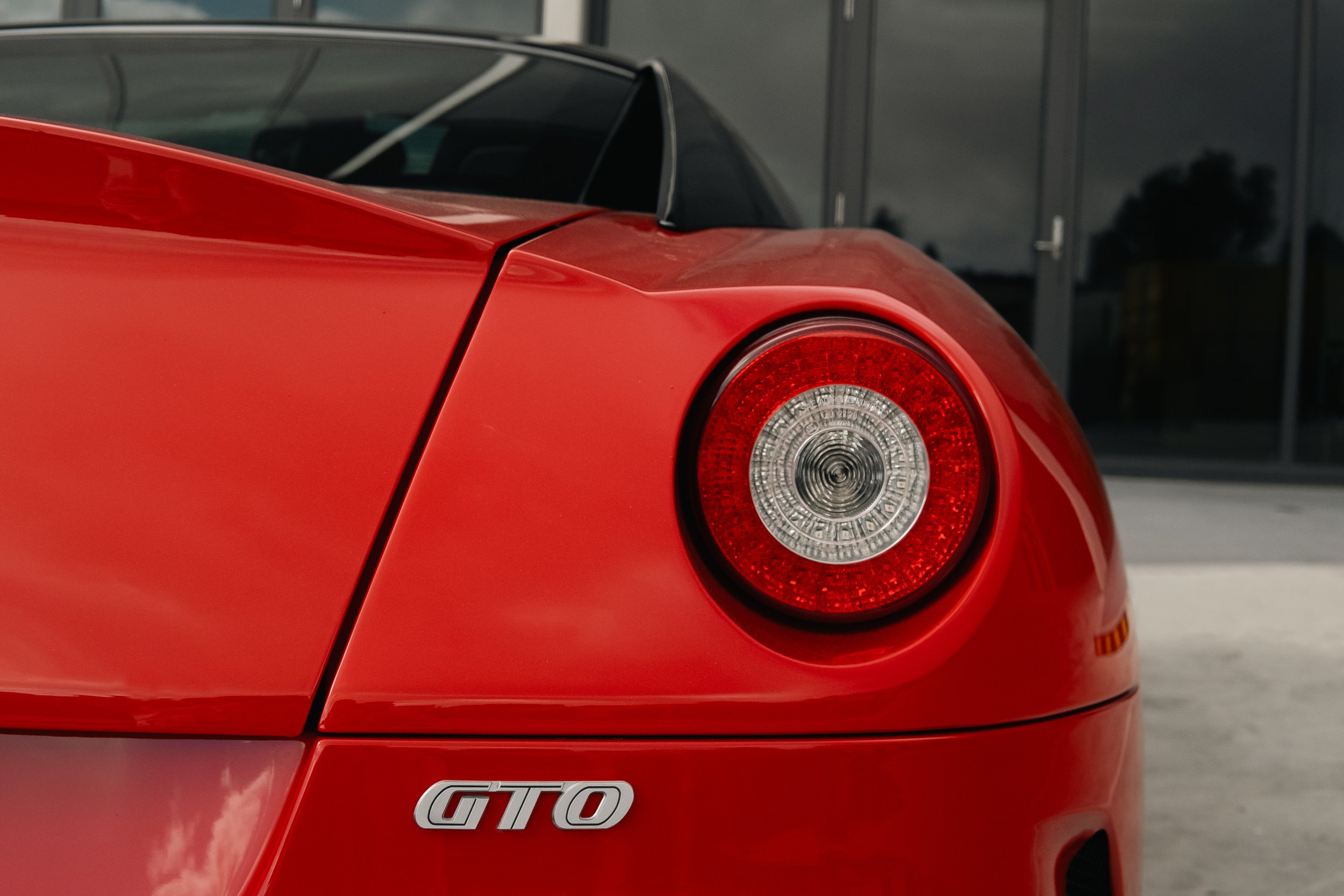 Close-up of the rear end of a red Ferrari GTO, showing the tail light and GTO badge on the trunk.