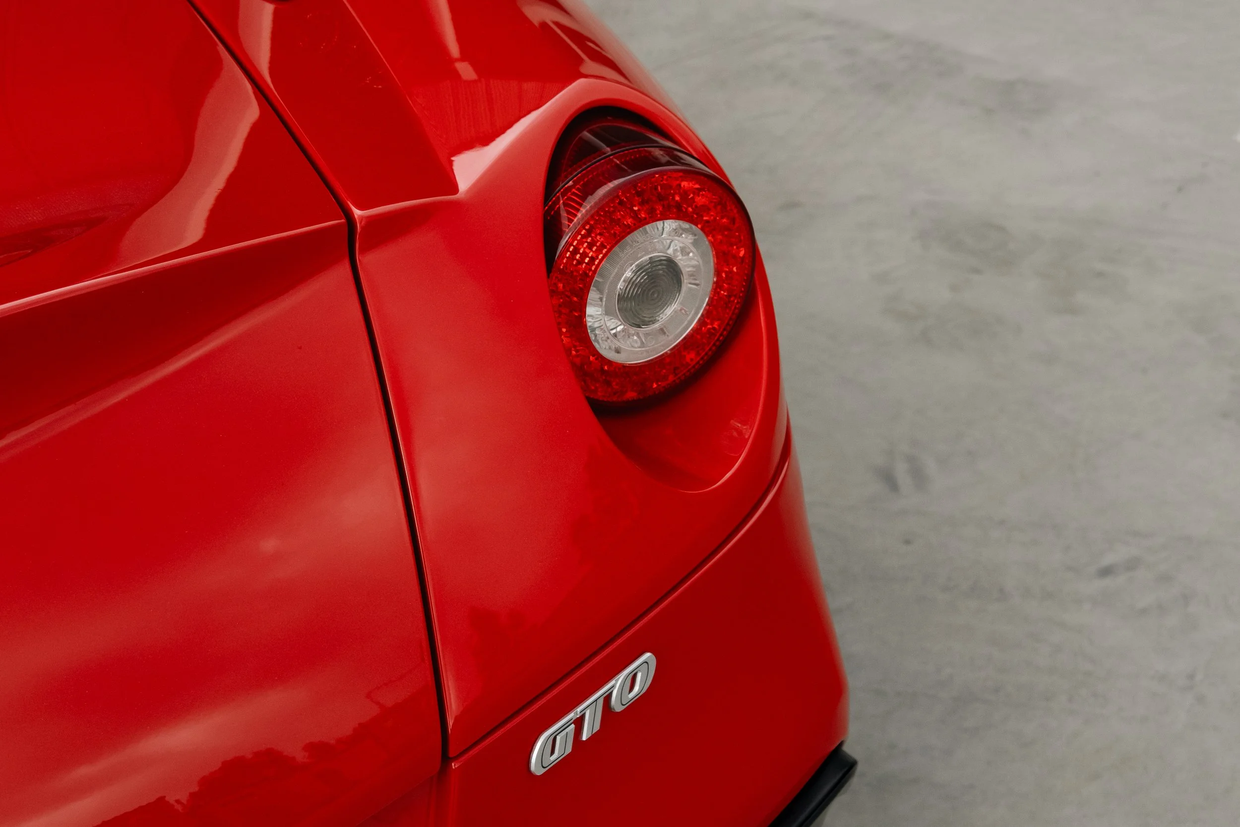 Rear corner of a red Porsche GTO sports car showing tail light and GTO badge.