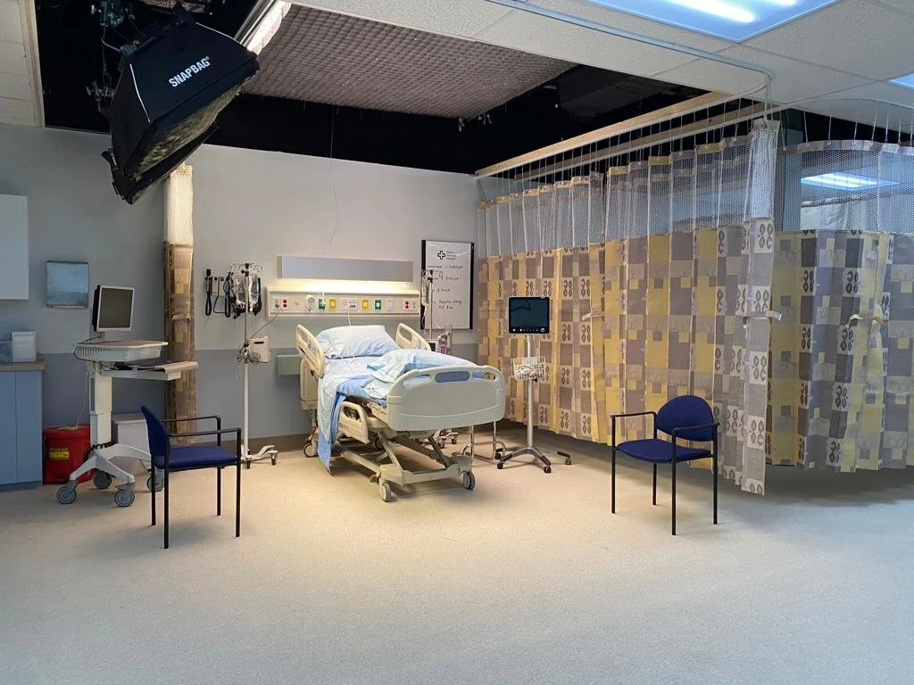 Empty hospital room with a bed, medical equipment, and privacy curtains.