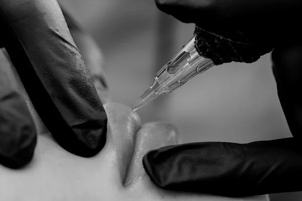 Raleigh Lip Blushing - Black and white photo, close up of lips and tattoo machine