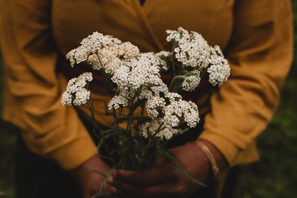 Person holding a bouquet of small white flowers, wearing a yellow jacket.