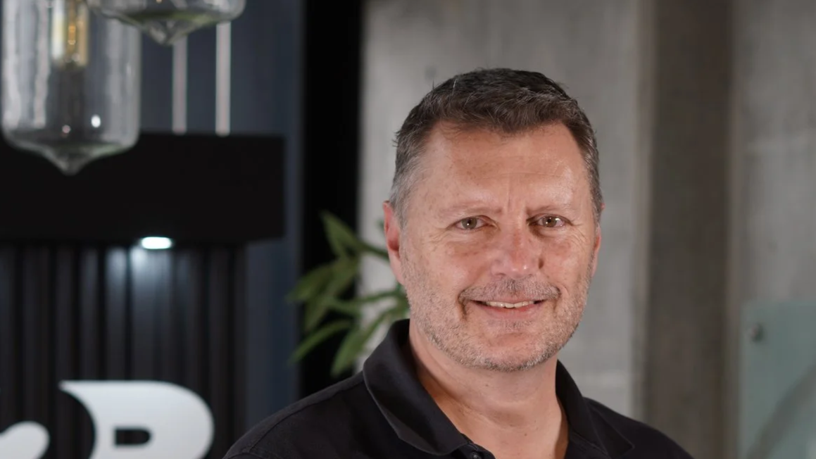 Hombre sonriendo con fondo de interior moderno y plantas decorativas