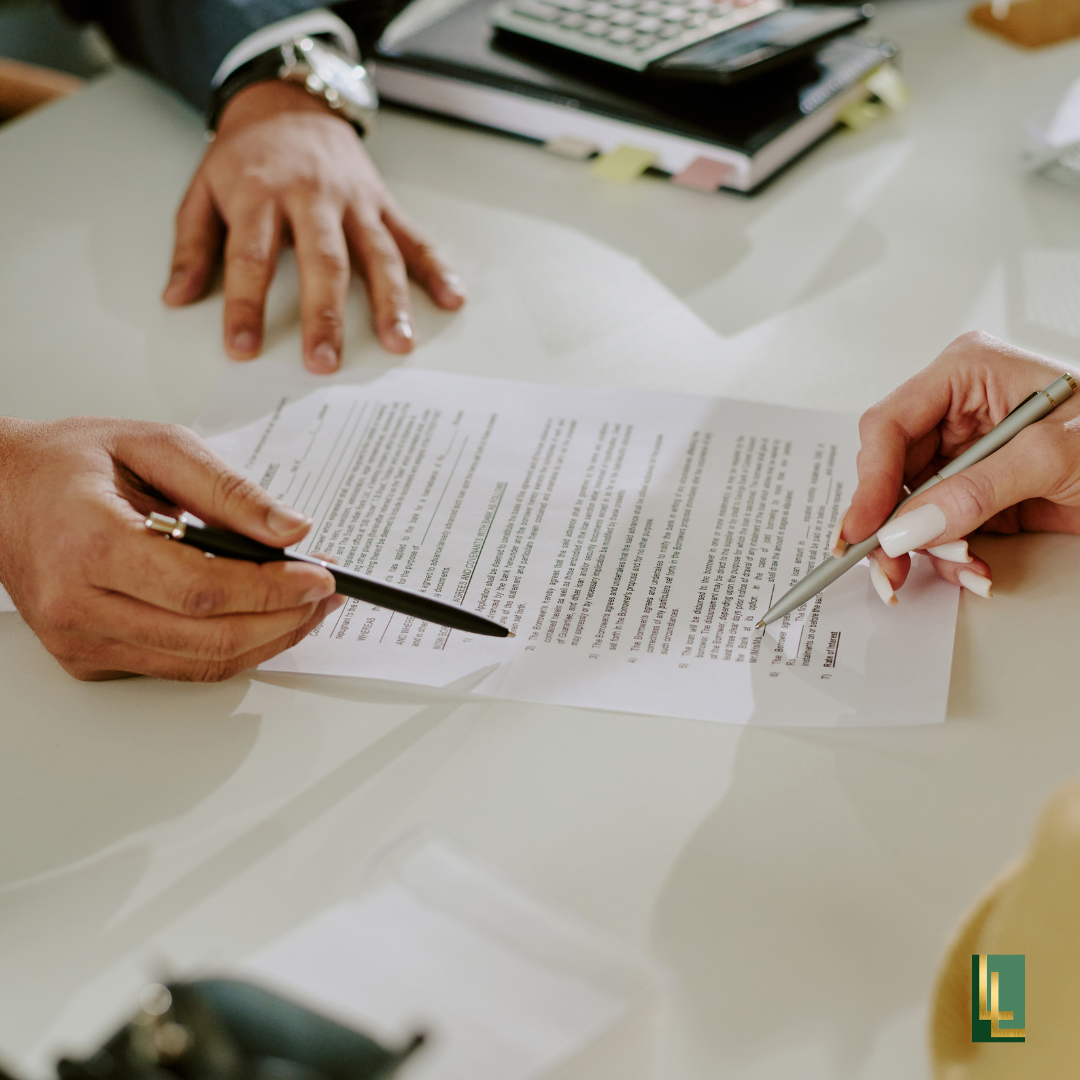 Close-up of two people signing a document at a desk with office supplies and a calculator in the background.