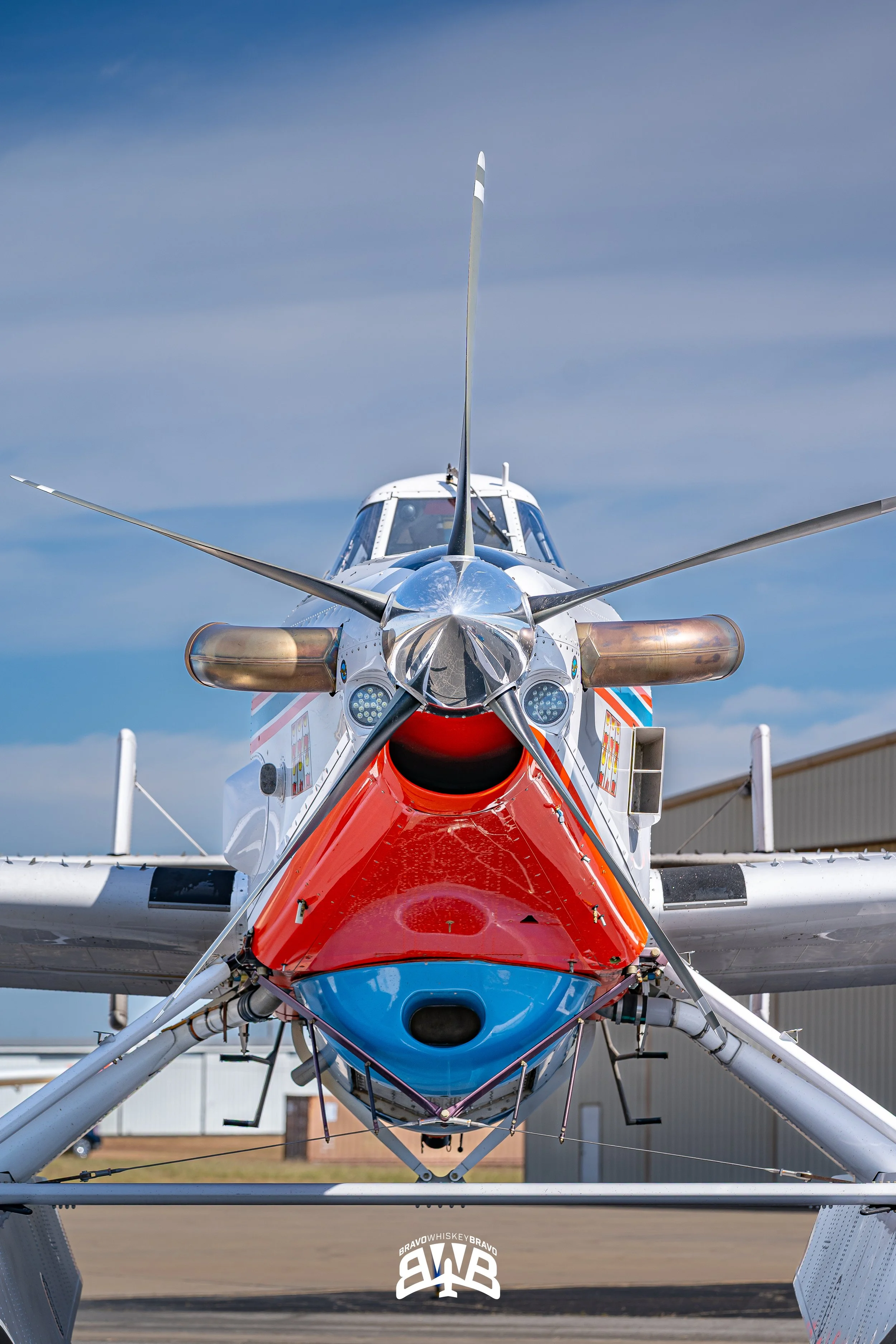 Front view of a helicopter with a colorful nose, propeller blades, and a clear sky background.